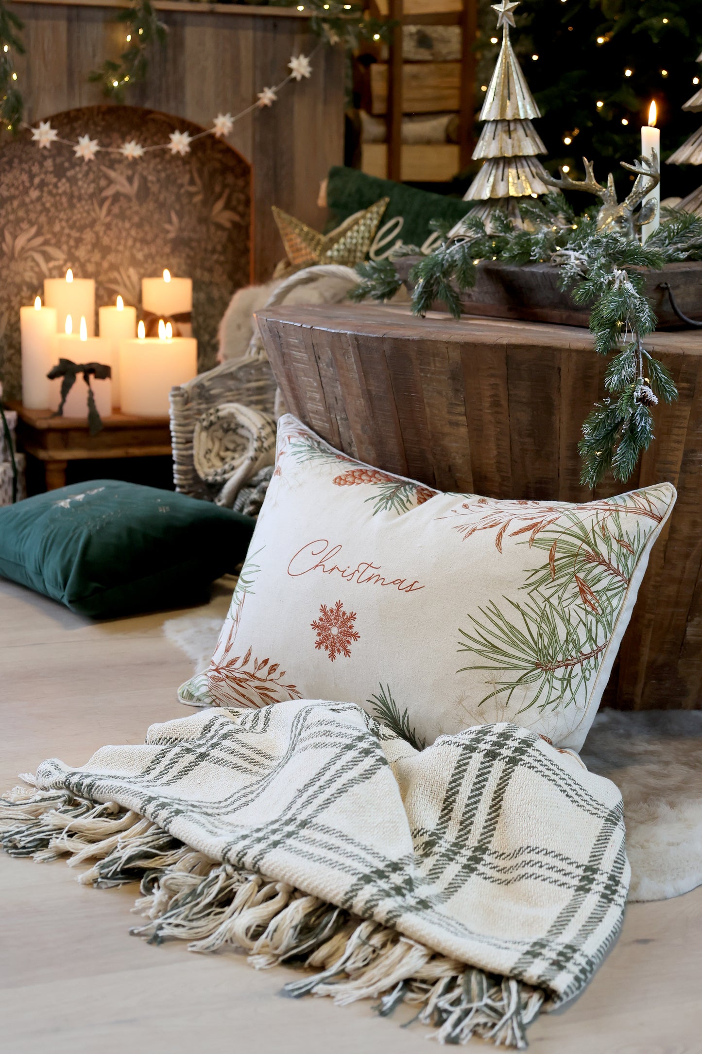 Decorative Christmas pillow with festive design on a bed with a blanket and candles.