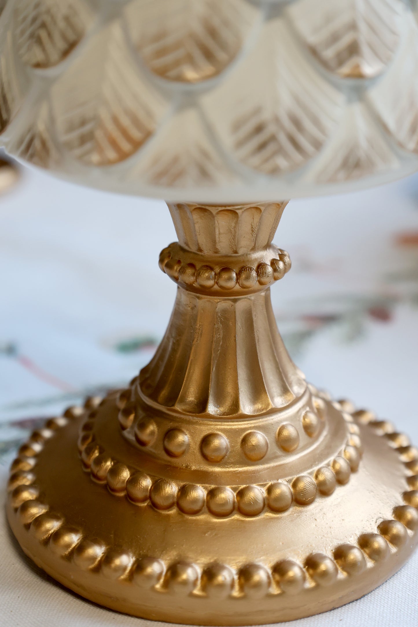 Decorative gold pedestal with intricate design on a light background