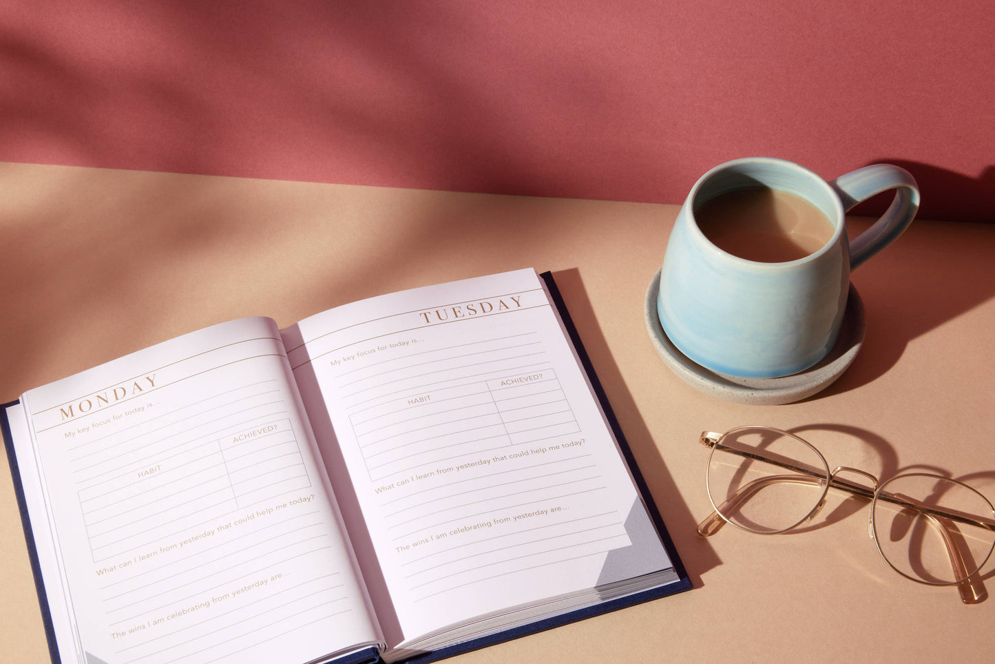 Open planner with a cup of coffee and glasses on a table