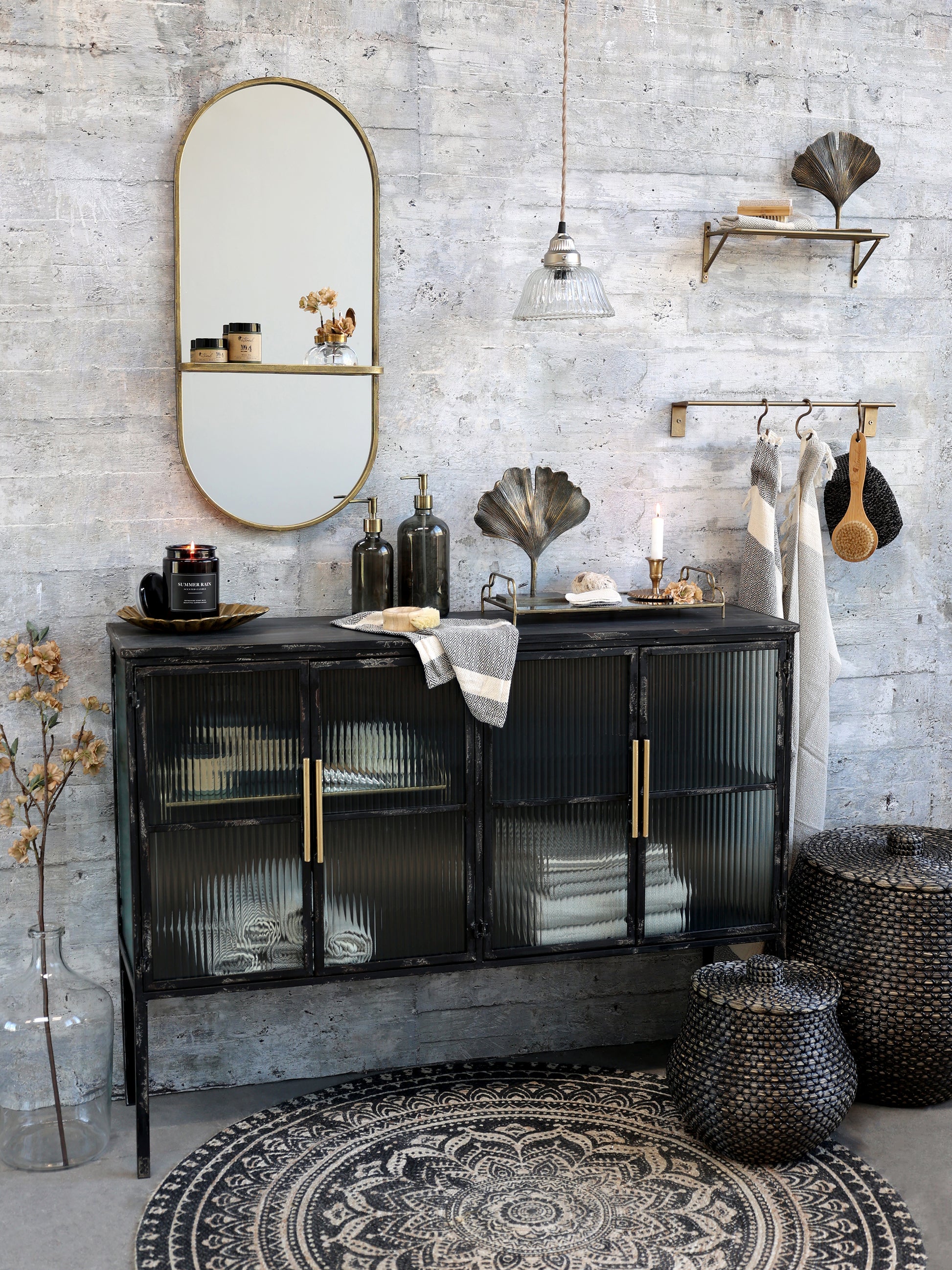 Black sideboard with gold handles in a room with a textured wall and decorative items.
