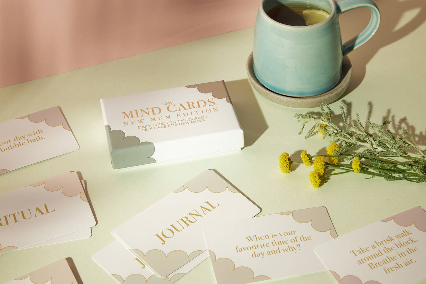 Table with 'Mind Cards' and a mug of tea, surrounded by cards and flowers.