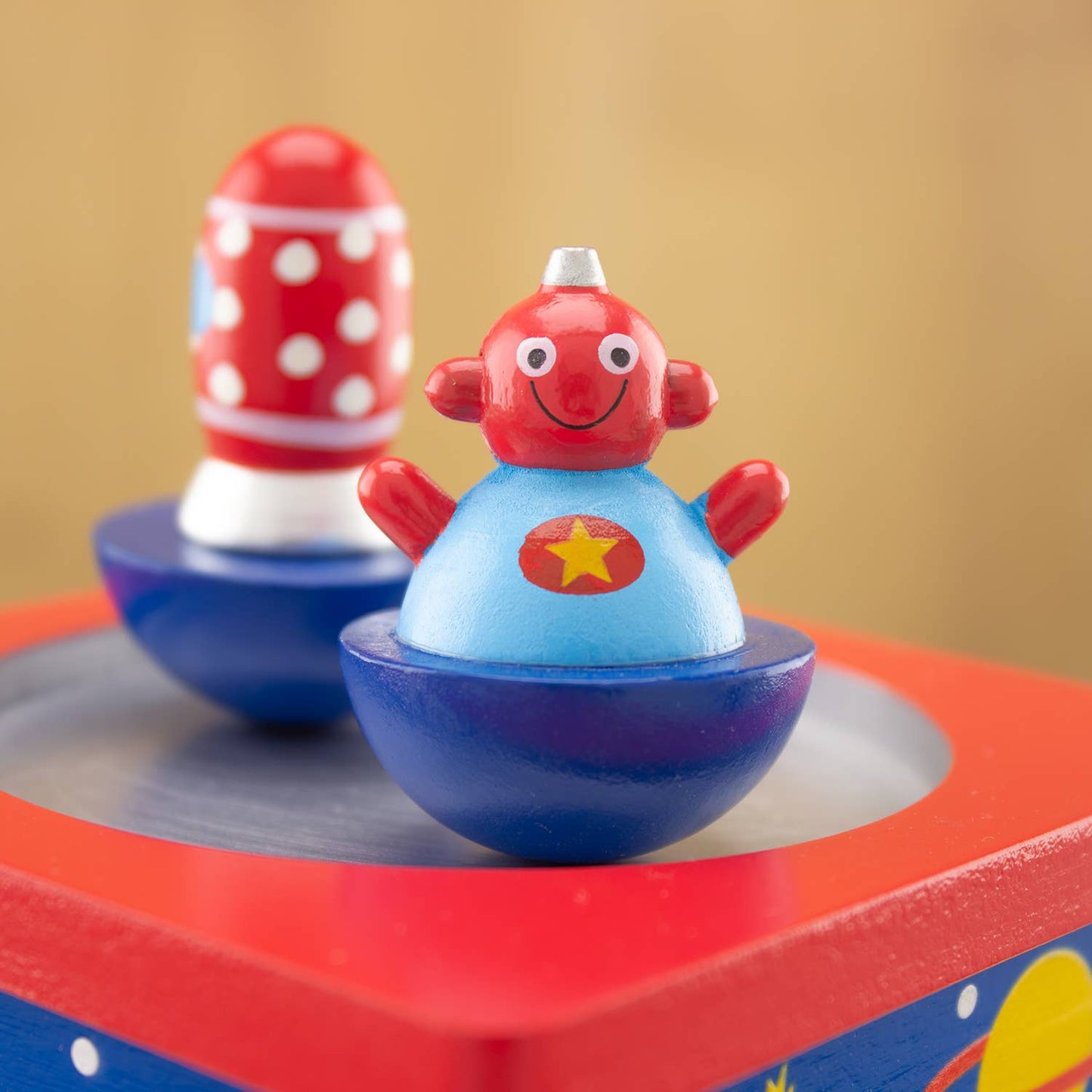 Two colorful spinning tops on a red base with a brown background