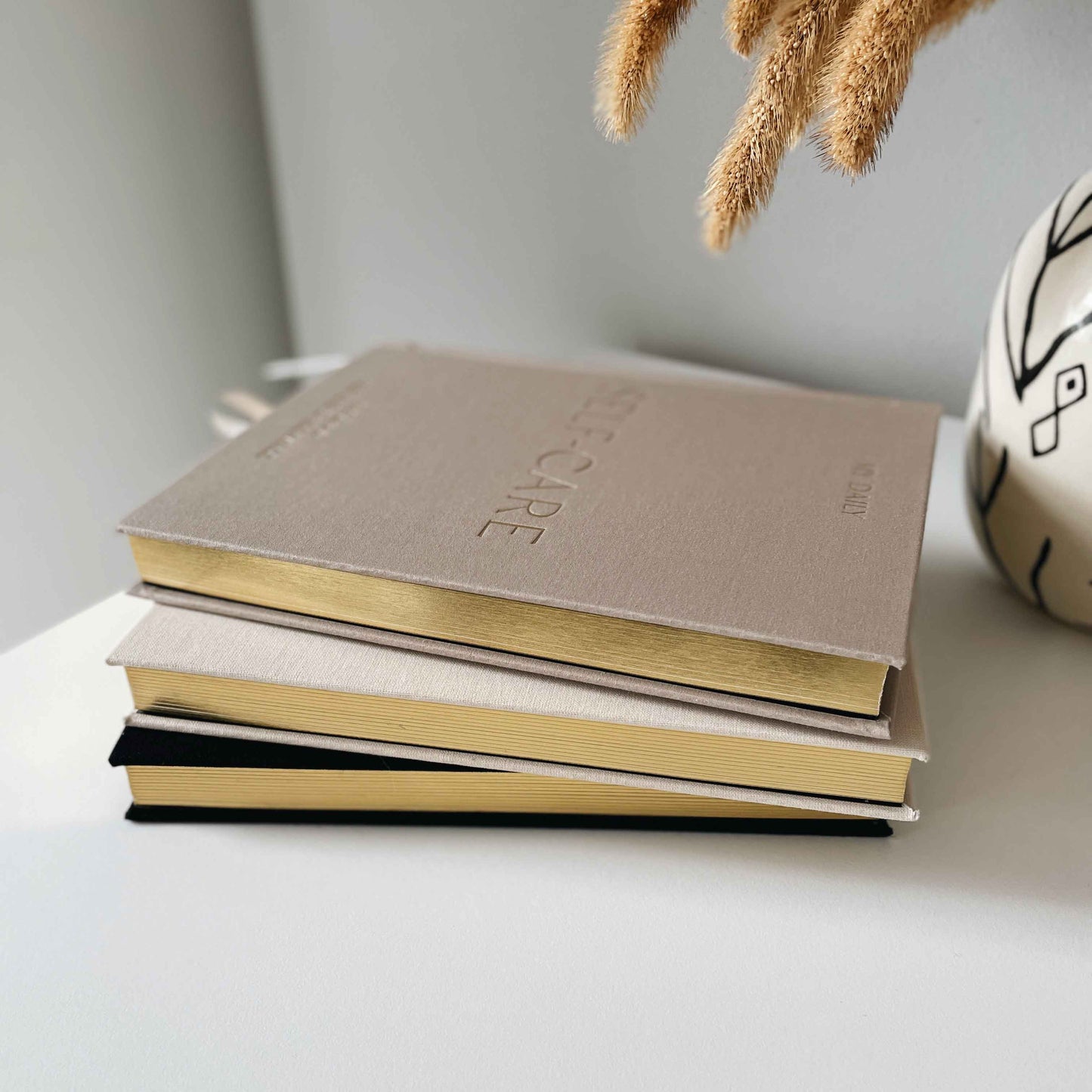 Stack of notebooks with 'Self-Care' on a white surface