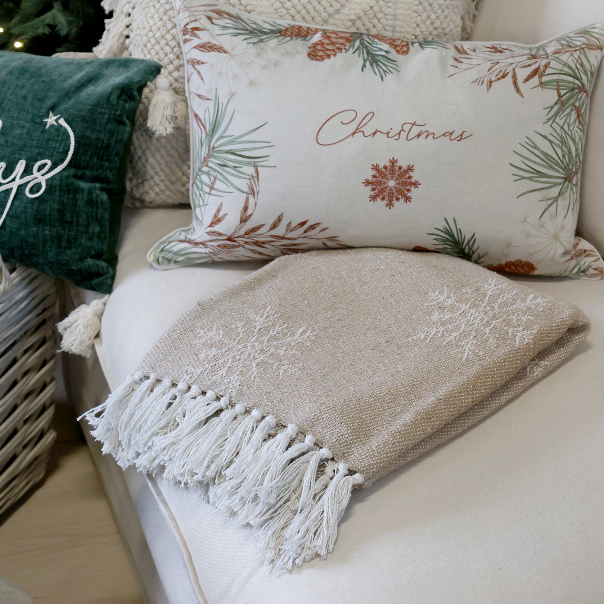 Decorative pillows and blanket on a couch with Christmas-themed designs.