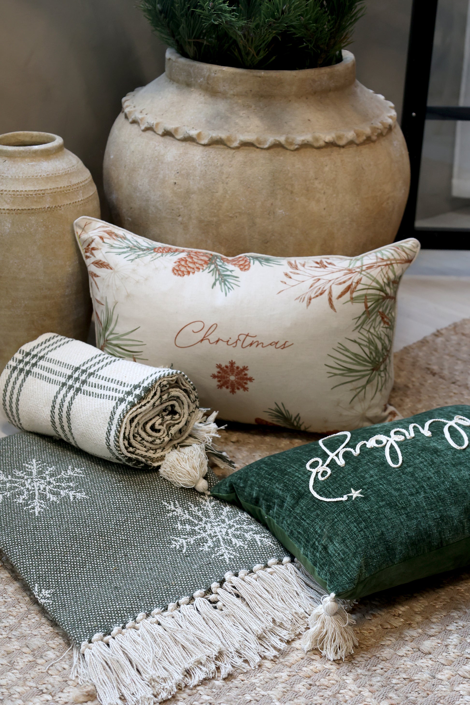 Decorative pillows and blanket with Christmas-themed designs on a textured surface.