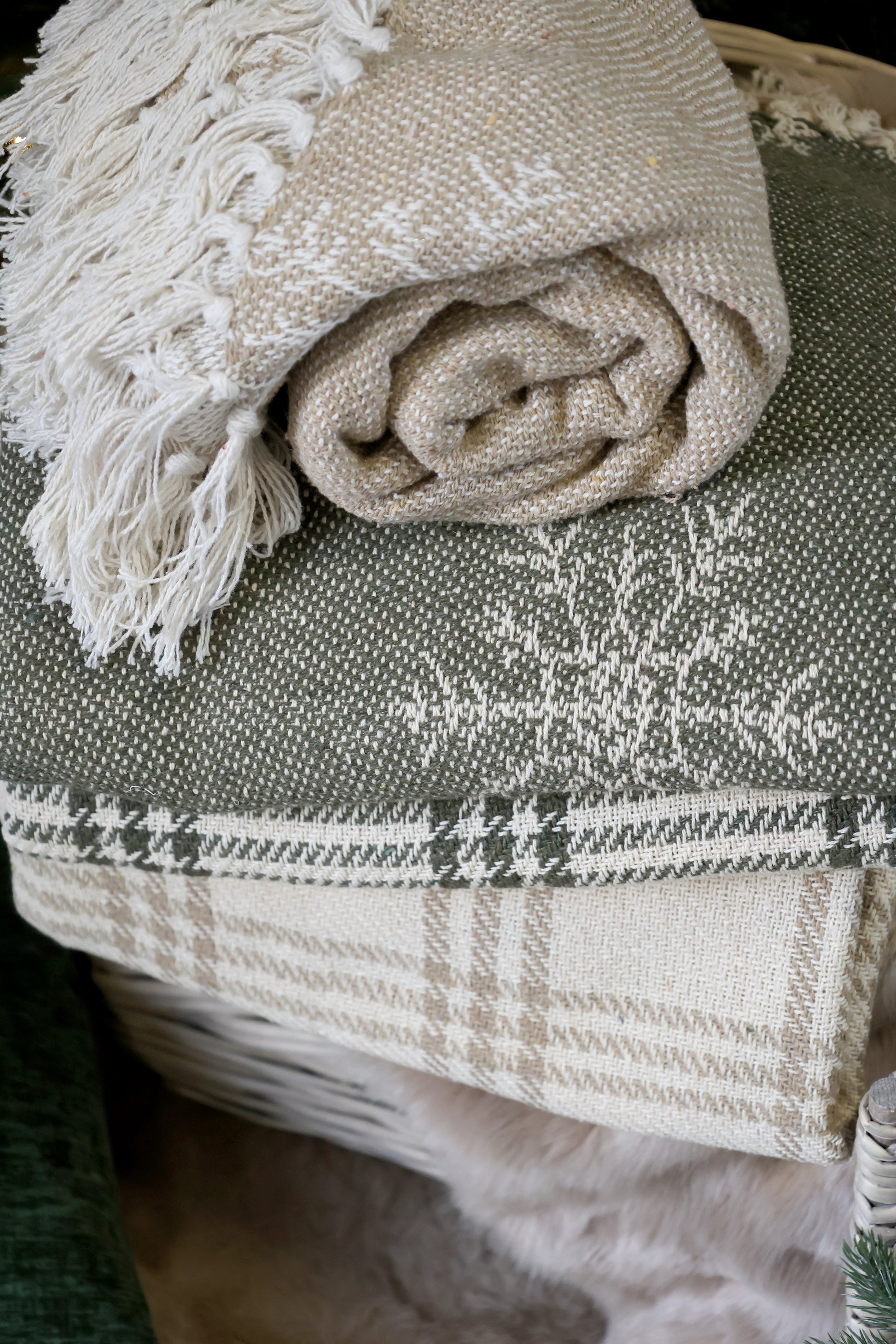 Folded beige blanket with tassels on a textured surface