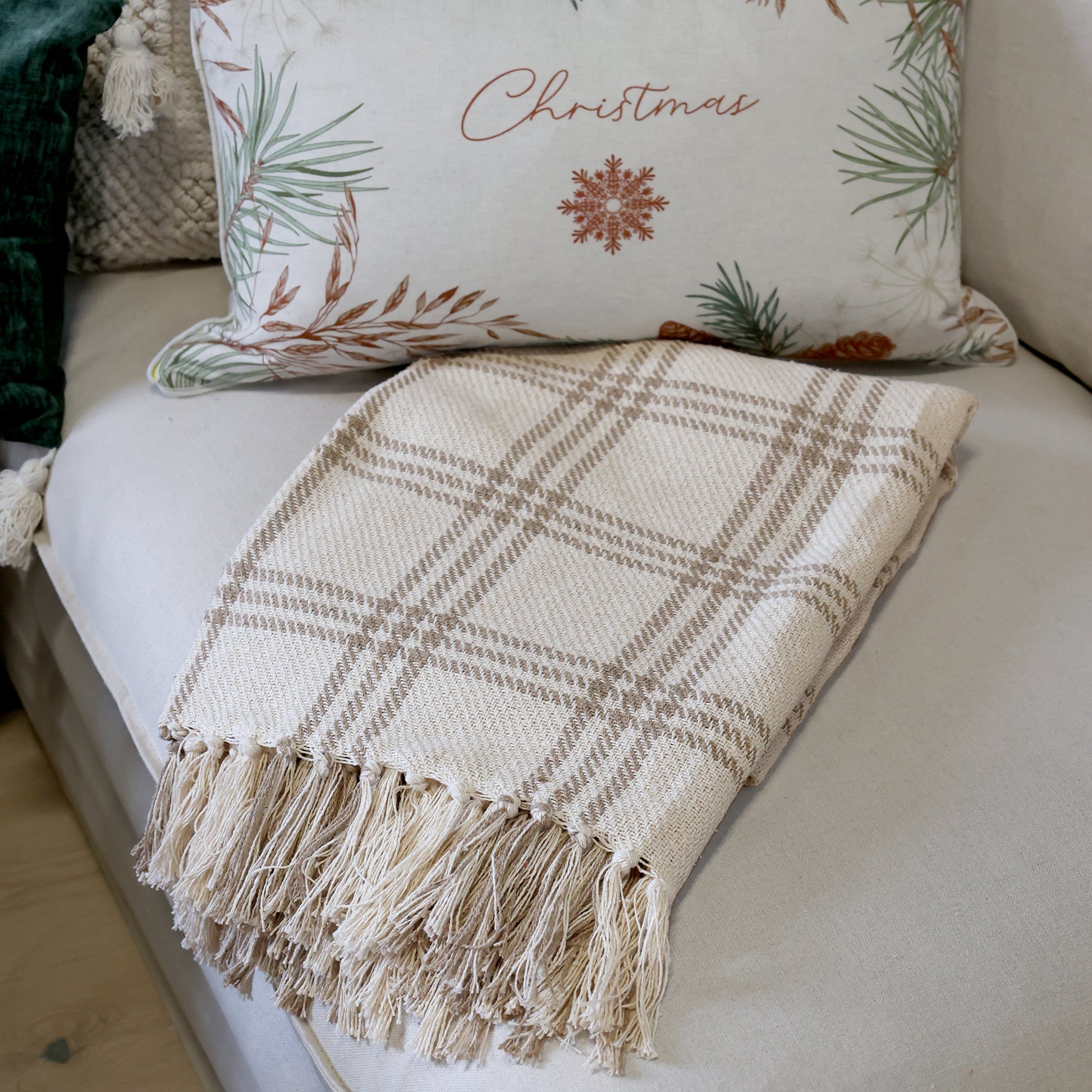 Plaid blanket with fringe on a sofa with Christmas-themed pillow