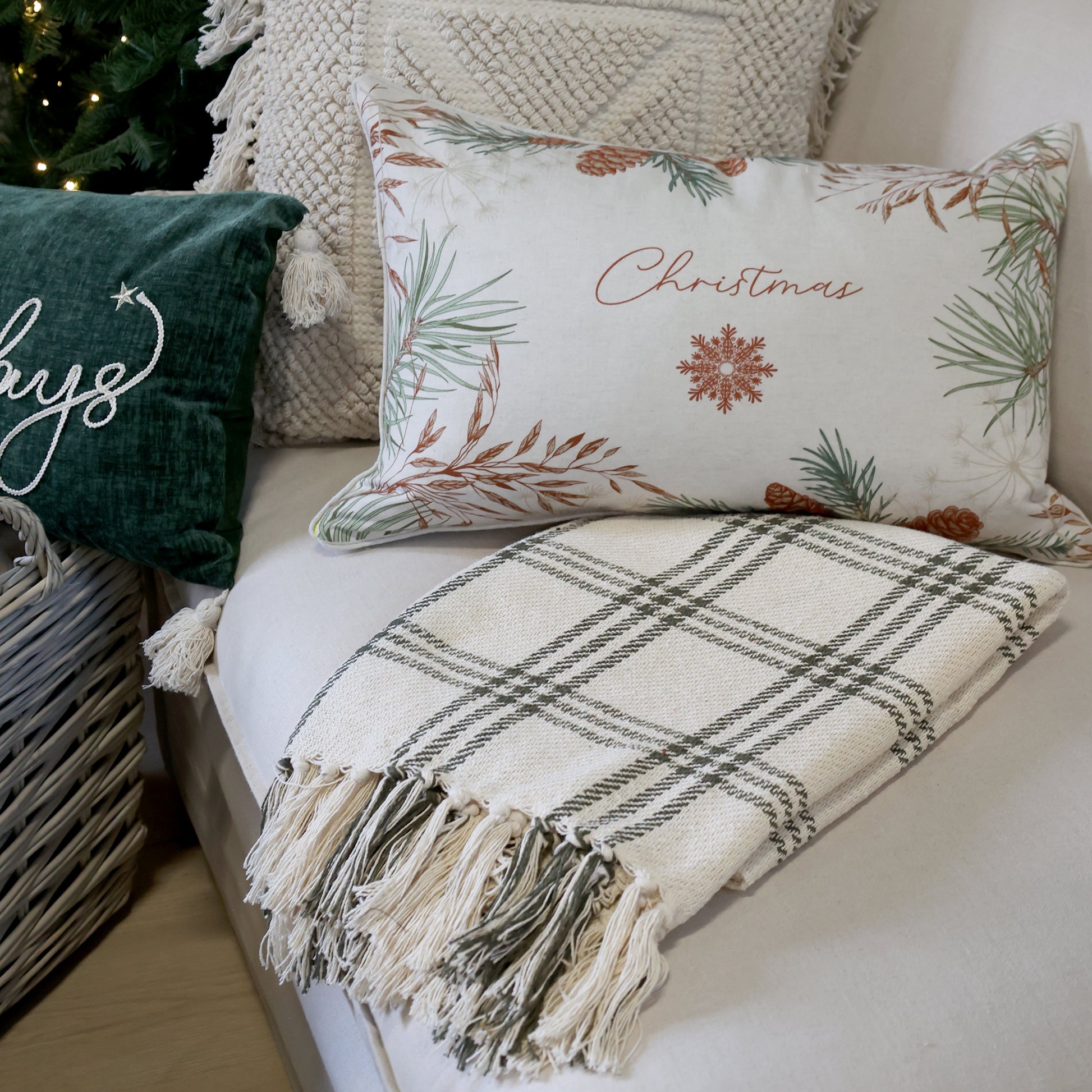 Decorative pillows and blanket on a couch with Christmas-themed designs