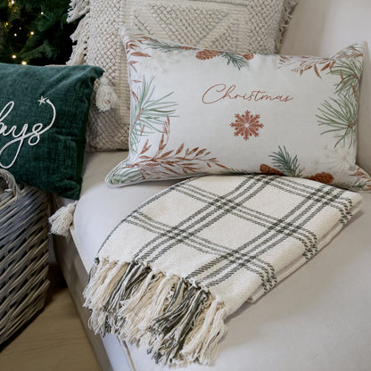 Decorative pillows and blanket on a couch with Christmas-themed designs