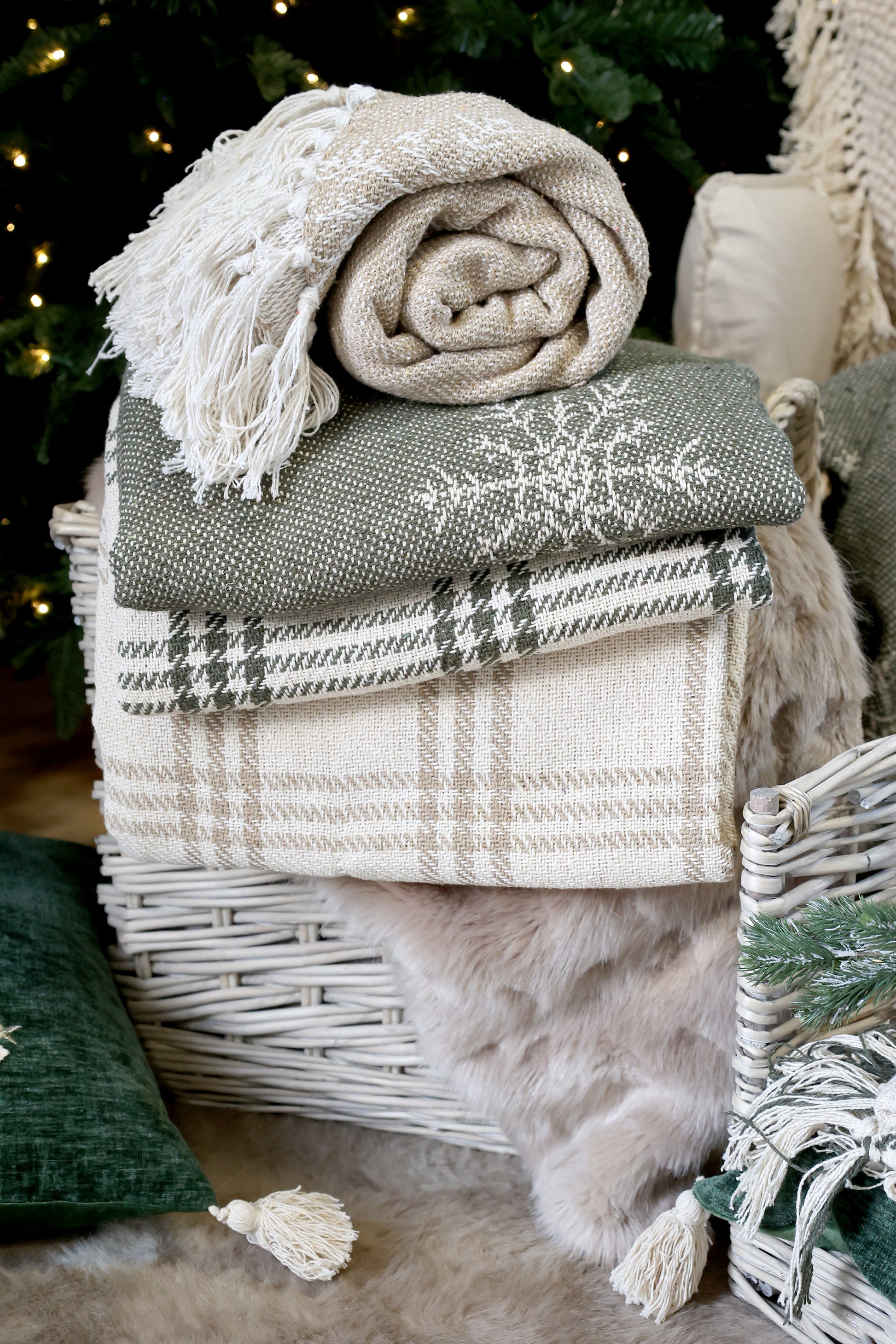 Stack of blankets on a wicker basket with a Christmas tree in the background