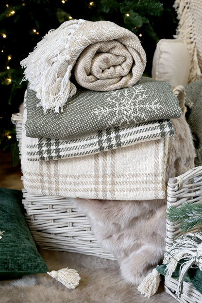 Stack of blankets on a wicker basket with a Christmas tree in the background