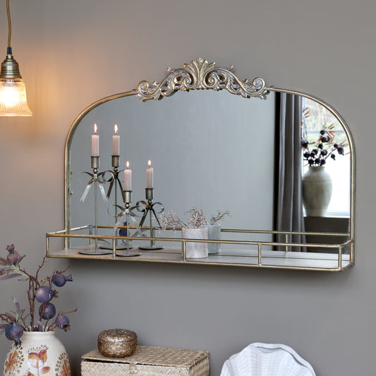 Decorative mirror with gold frame on a gray wall, with candles and decorative items.
