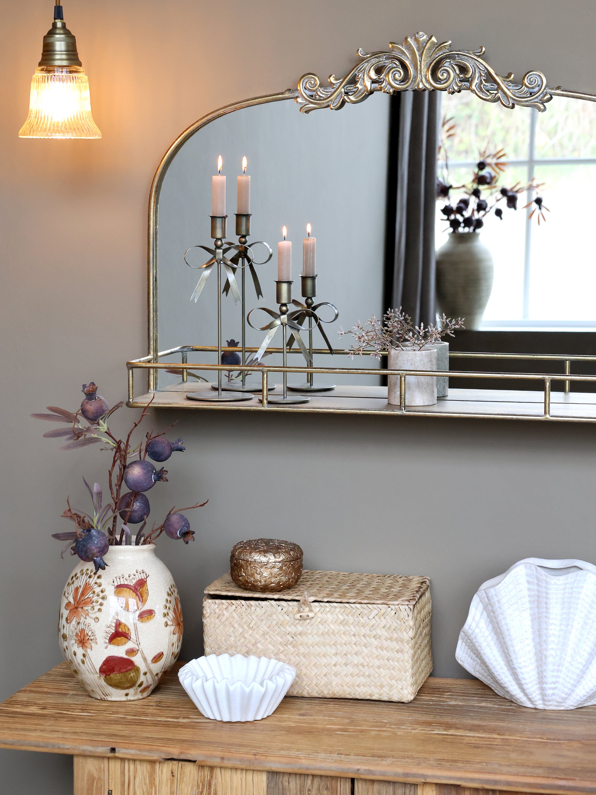 Decorative items on a wooden console table with a large mirror above.