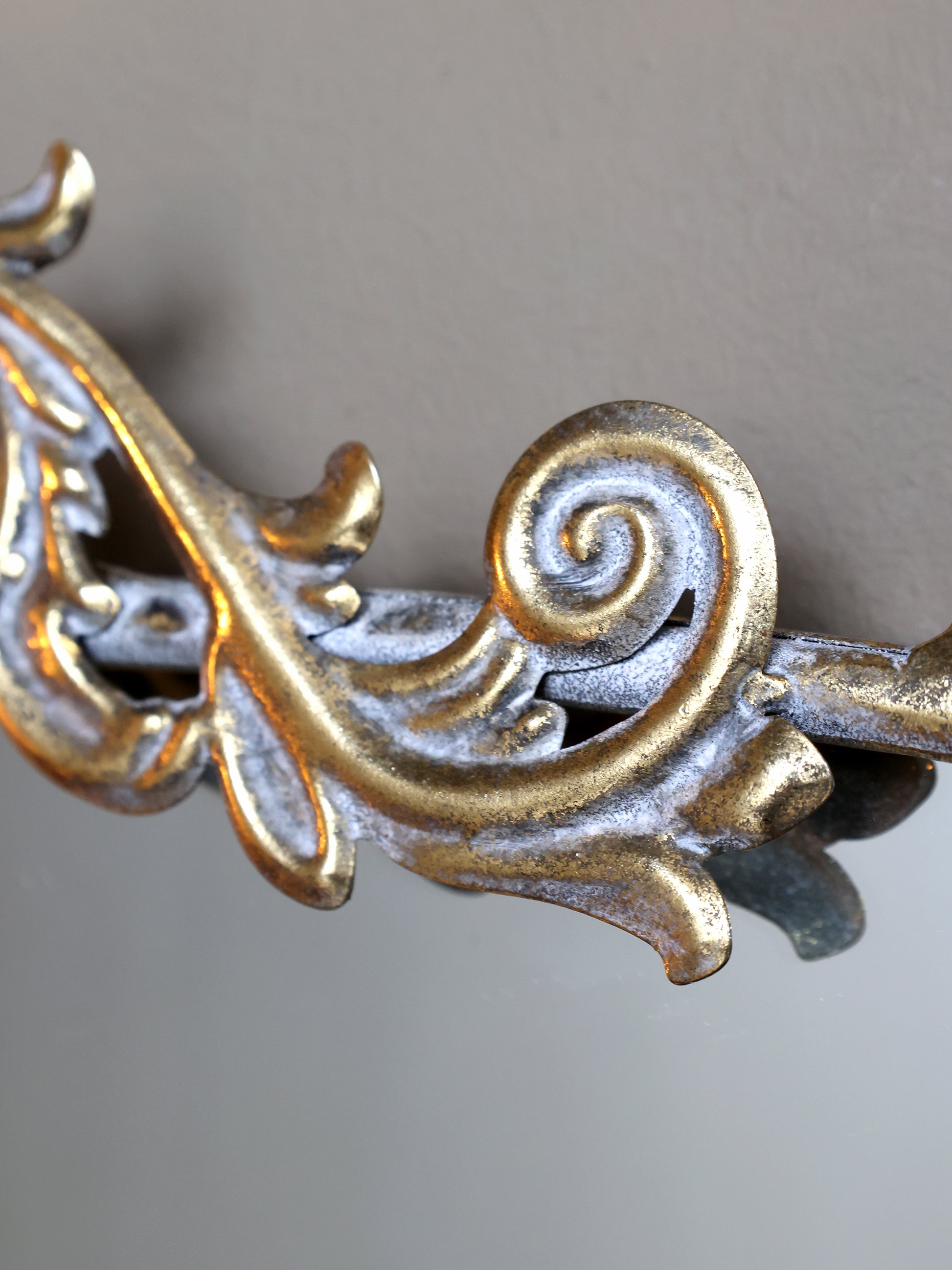Decorative metal bracket with intricate designs on a neutral background