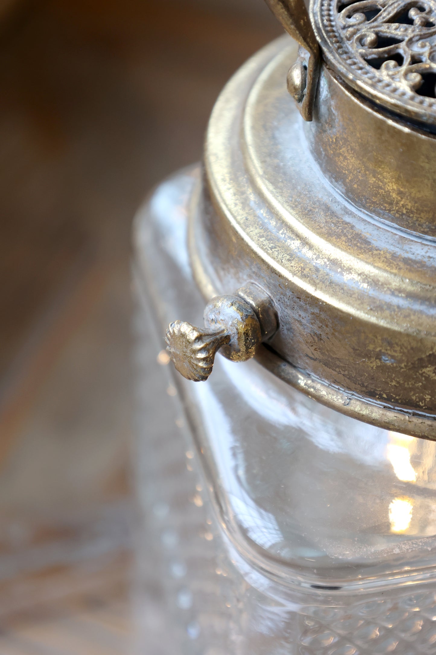 Close-up of a vintage-style lantern with metallic top and clear glass body.