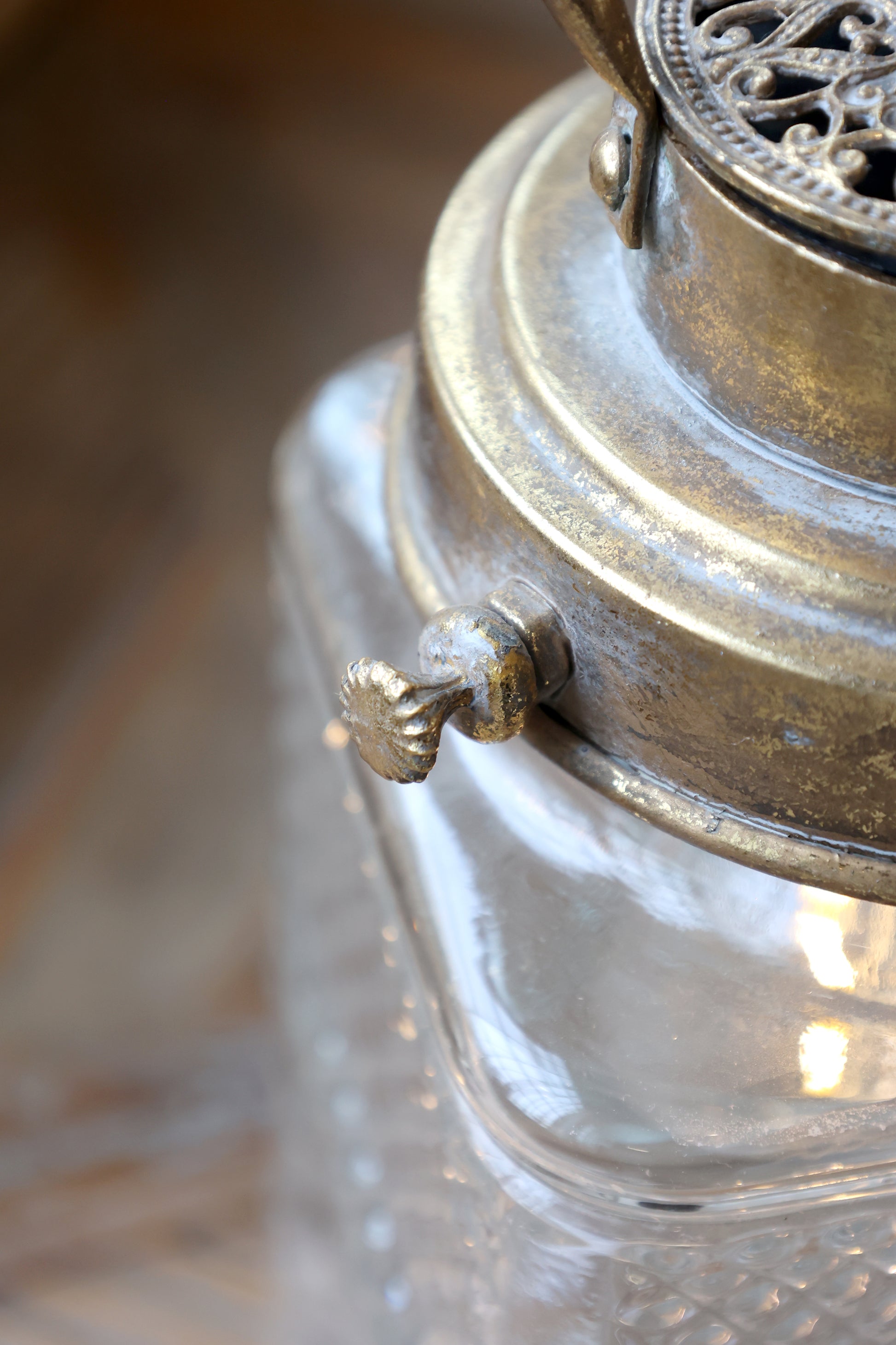 Close-up of a vintage-style lantern with metallic top and clear glass body.