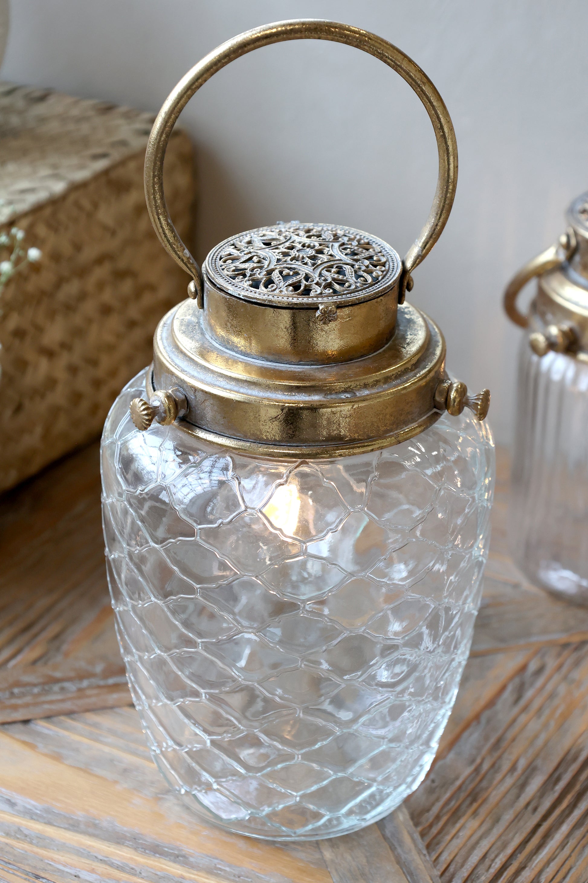 Decorative glass lantern with brass handle and top on a wooden surface
