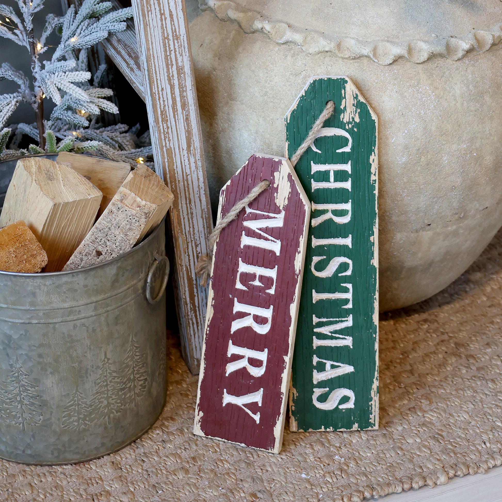 Two Christmas-themed wooden signs, one red and one green, leaning against a decorative background.