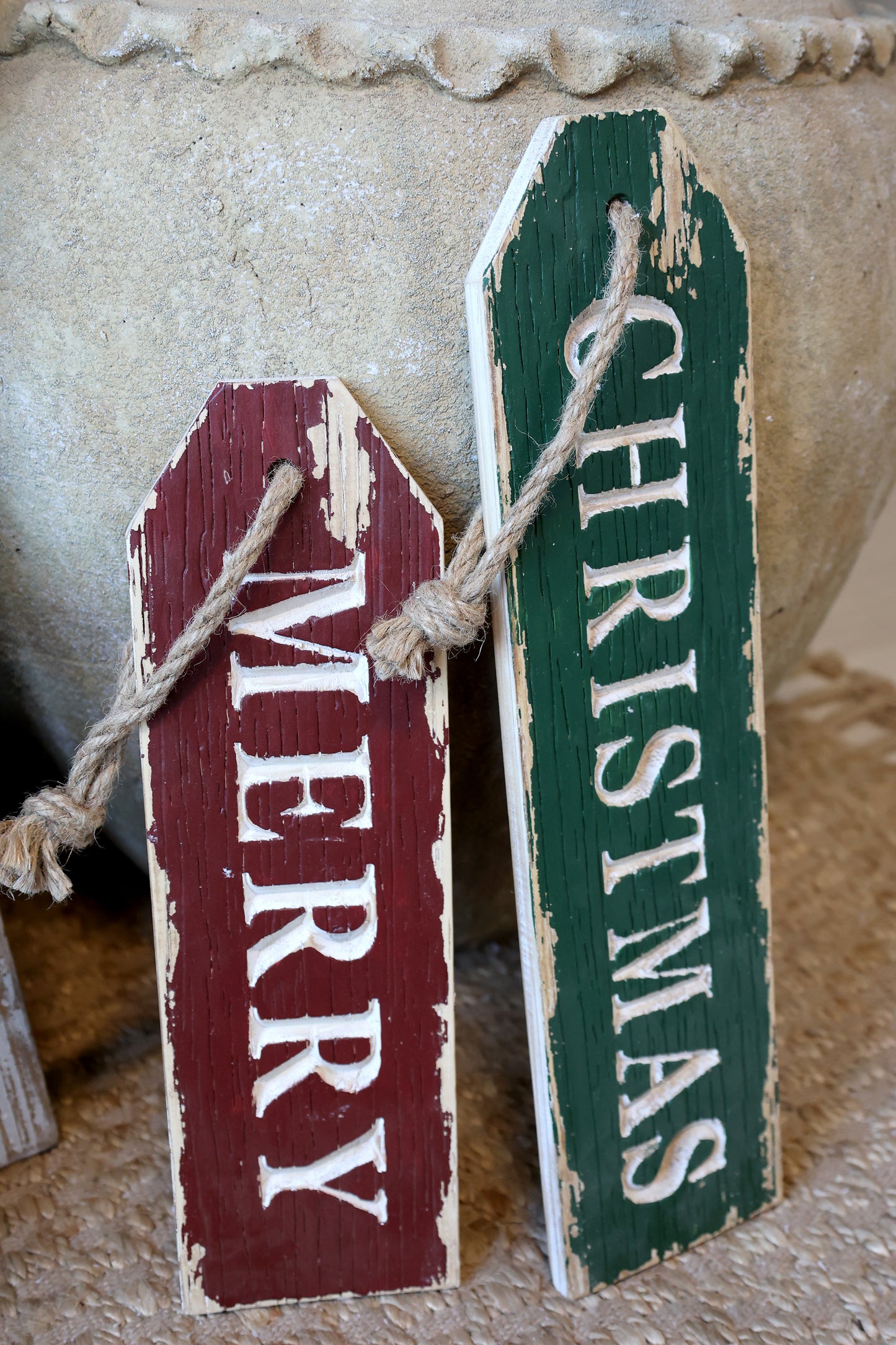 Two wooden Christmas signs, one red and one green, with 'Merry' and 'Christmas' text.