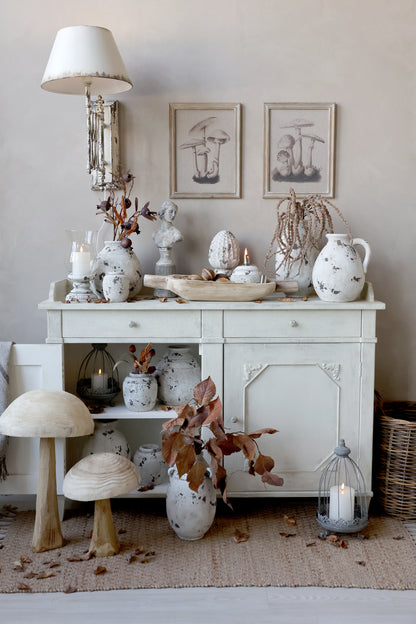 Decorative interior with a white sideboard, vases, and candles on a neutral background