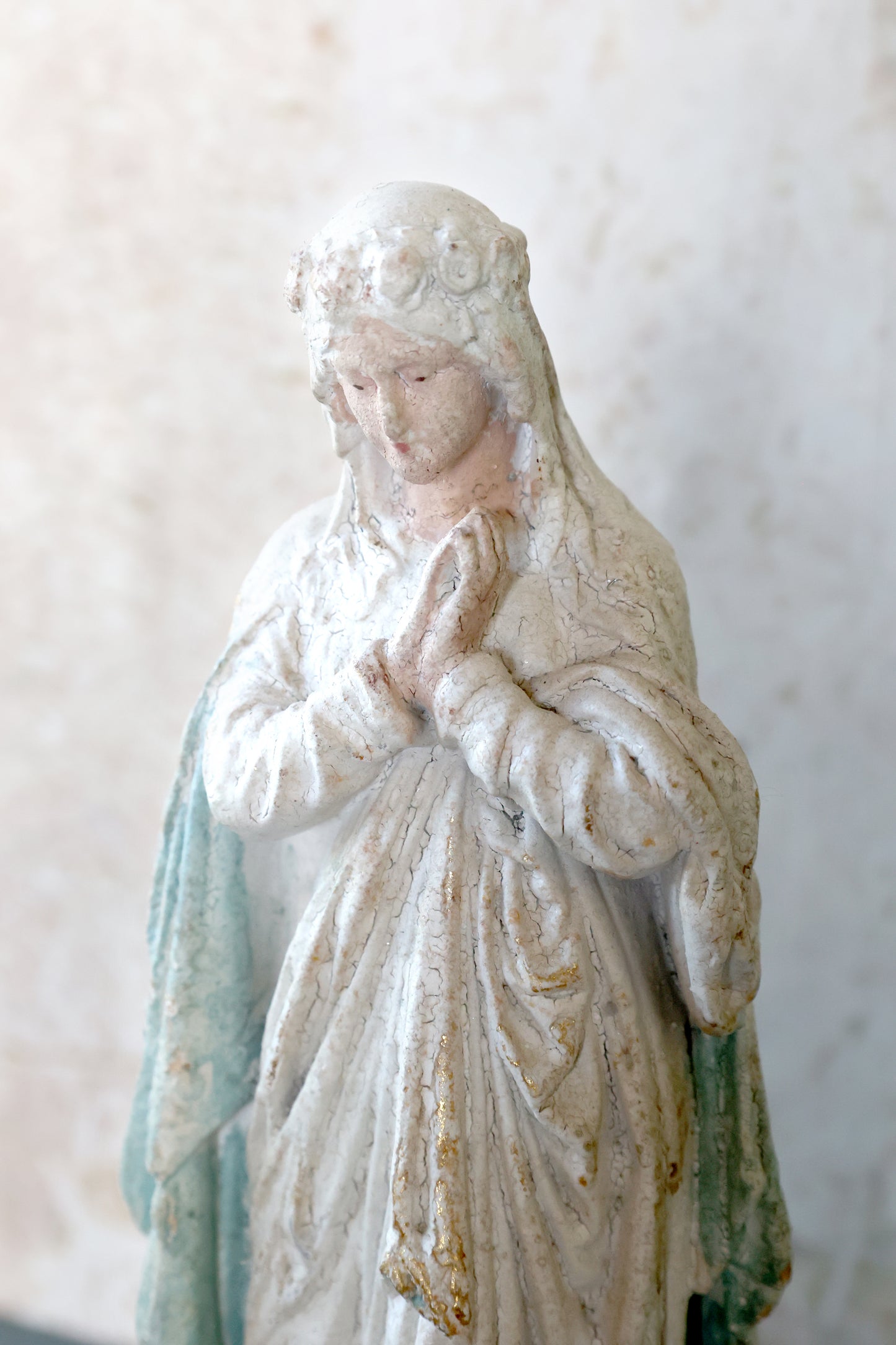 Statue of a religious figure with a white and green robe against a light background