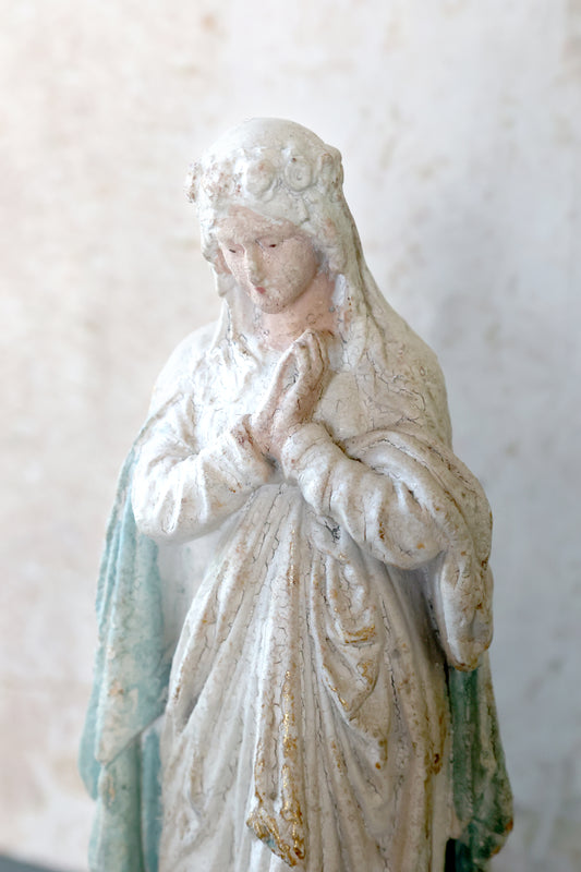 Statue of a religious figure with a white and green robe against a light background