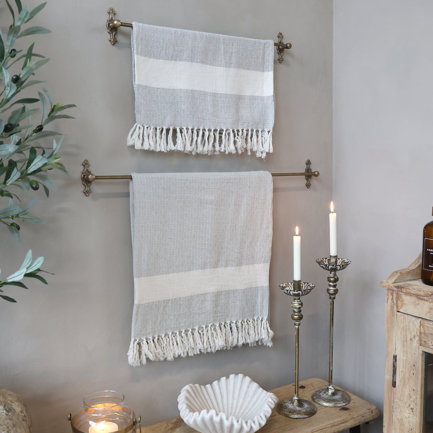 Two striped towels hanging on a towel rack with candles and a plant in the background.