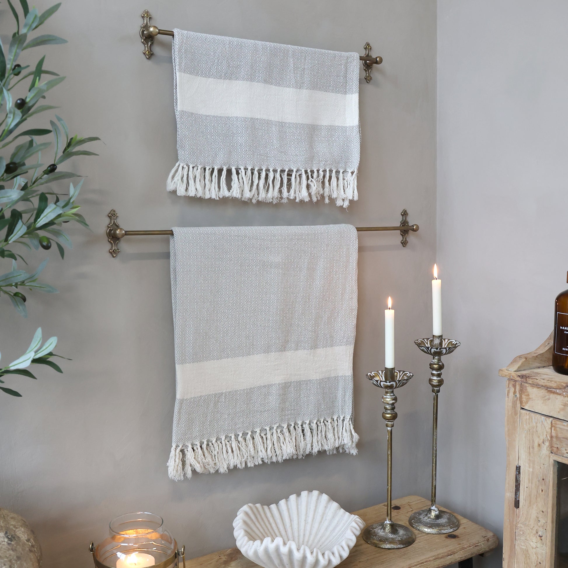 Two striped towels hanging on a towel rack with candles and a plant in the background.