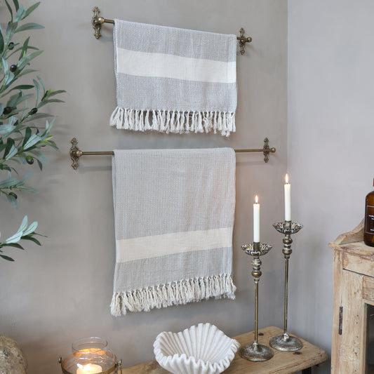 Two striped towels hanging on a towel rack with candles and a plant in the background.