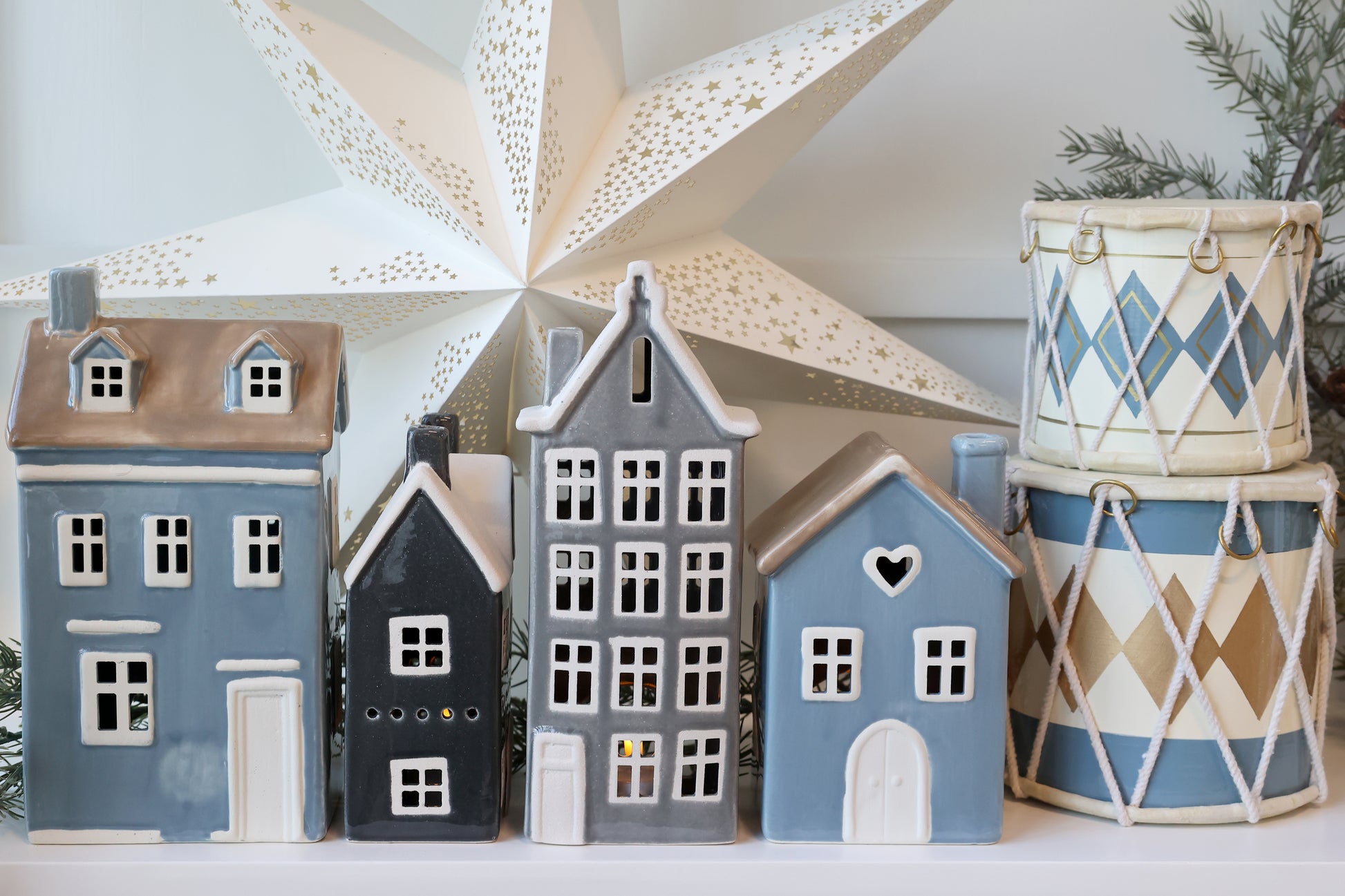 Decorative ceramic houses and patterned drums against a white background