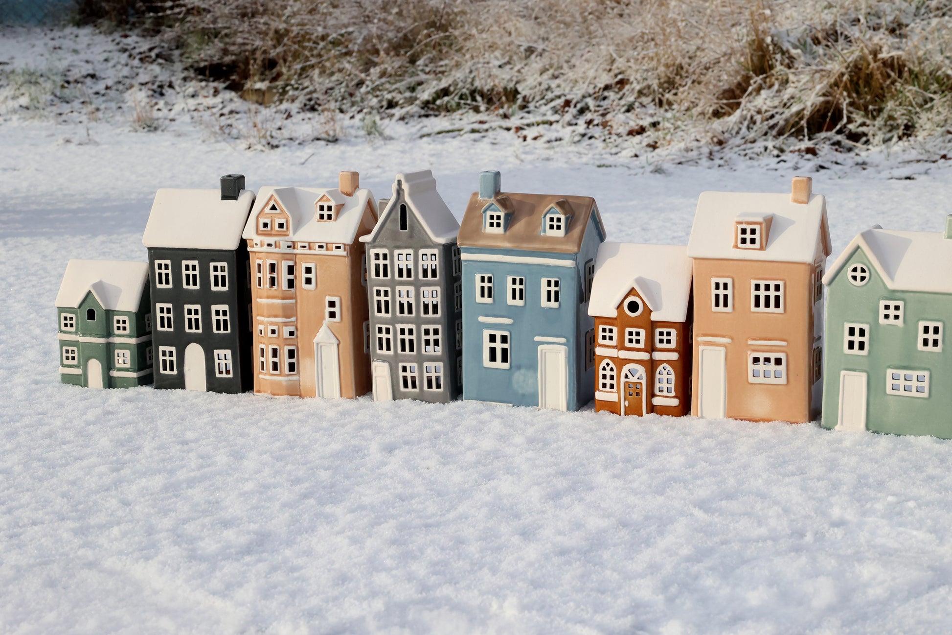 Row of small model houses in various colors on a snowy landscape