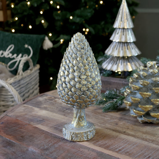 Decorative pine cone on a wooden surface with Christmas decorations in the background