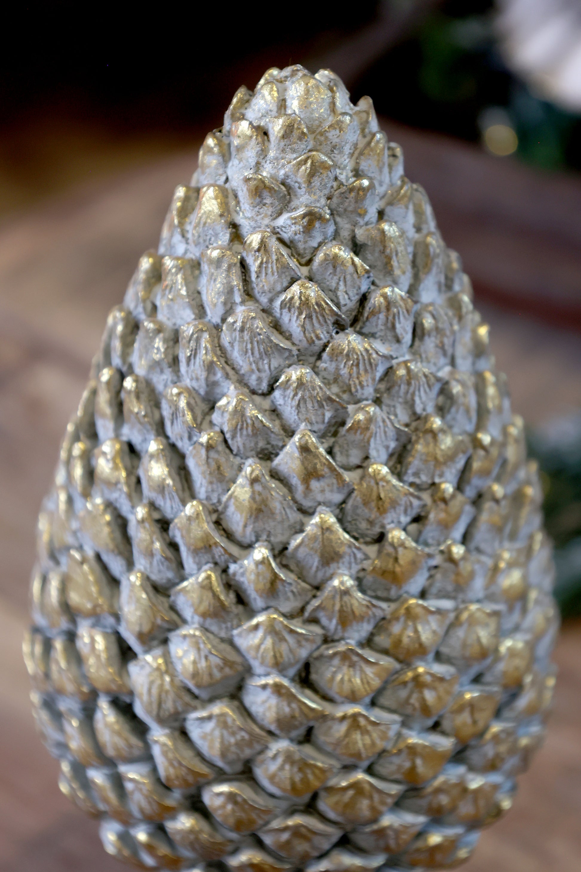 Decorative pine cone sculpture with a textured surface on a blurred background
