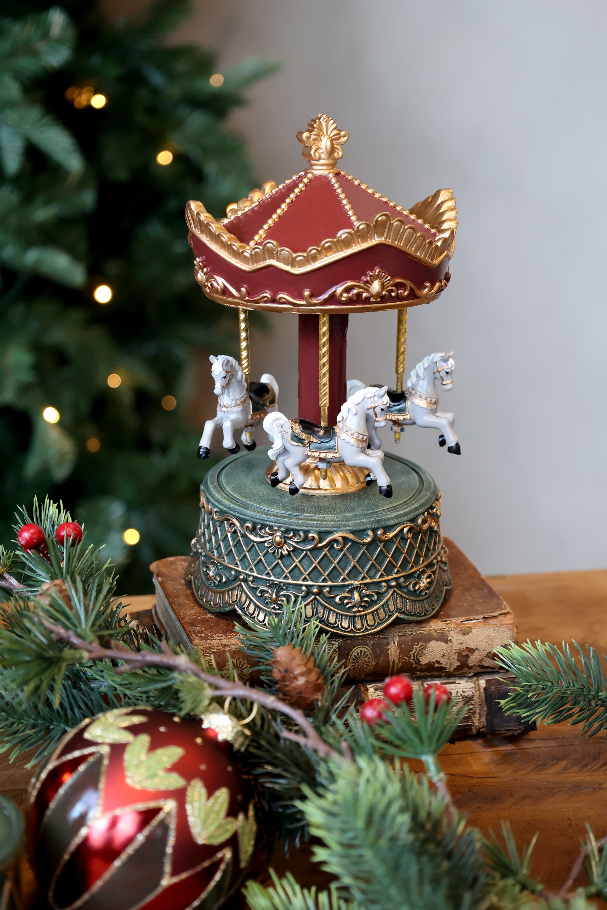 Decorative carousel music box with horses on a Christmas tree branch.