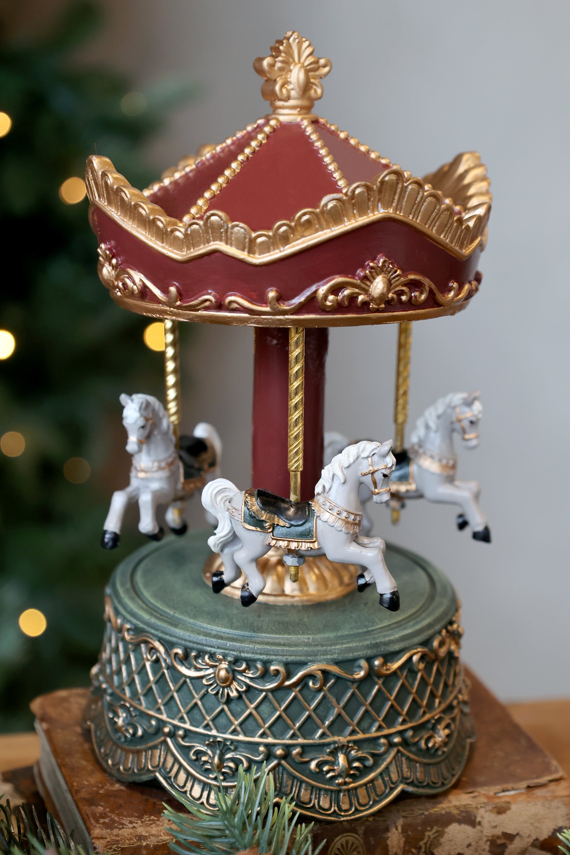 Decorative carousel with horses on a wooden surface, Christmas tree in the background