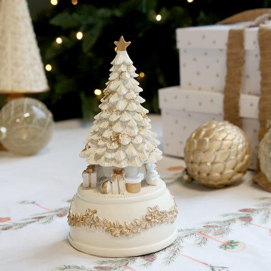 Decorative Christmas tree figurine with gold accents on a table with festive background