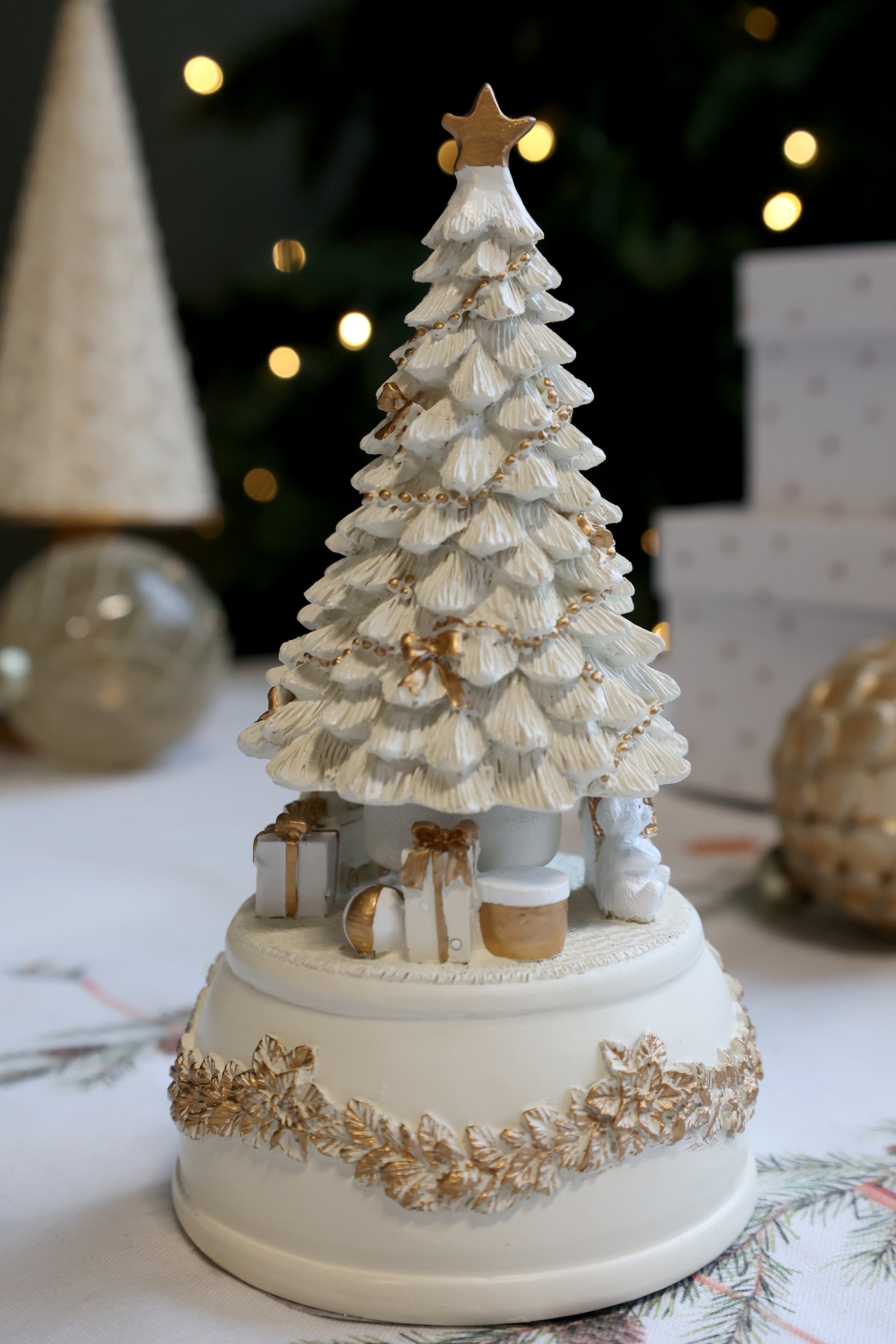 Decorative ceramic Christmas tree with gold accents on a table with festive background
