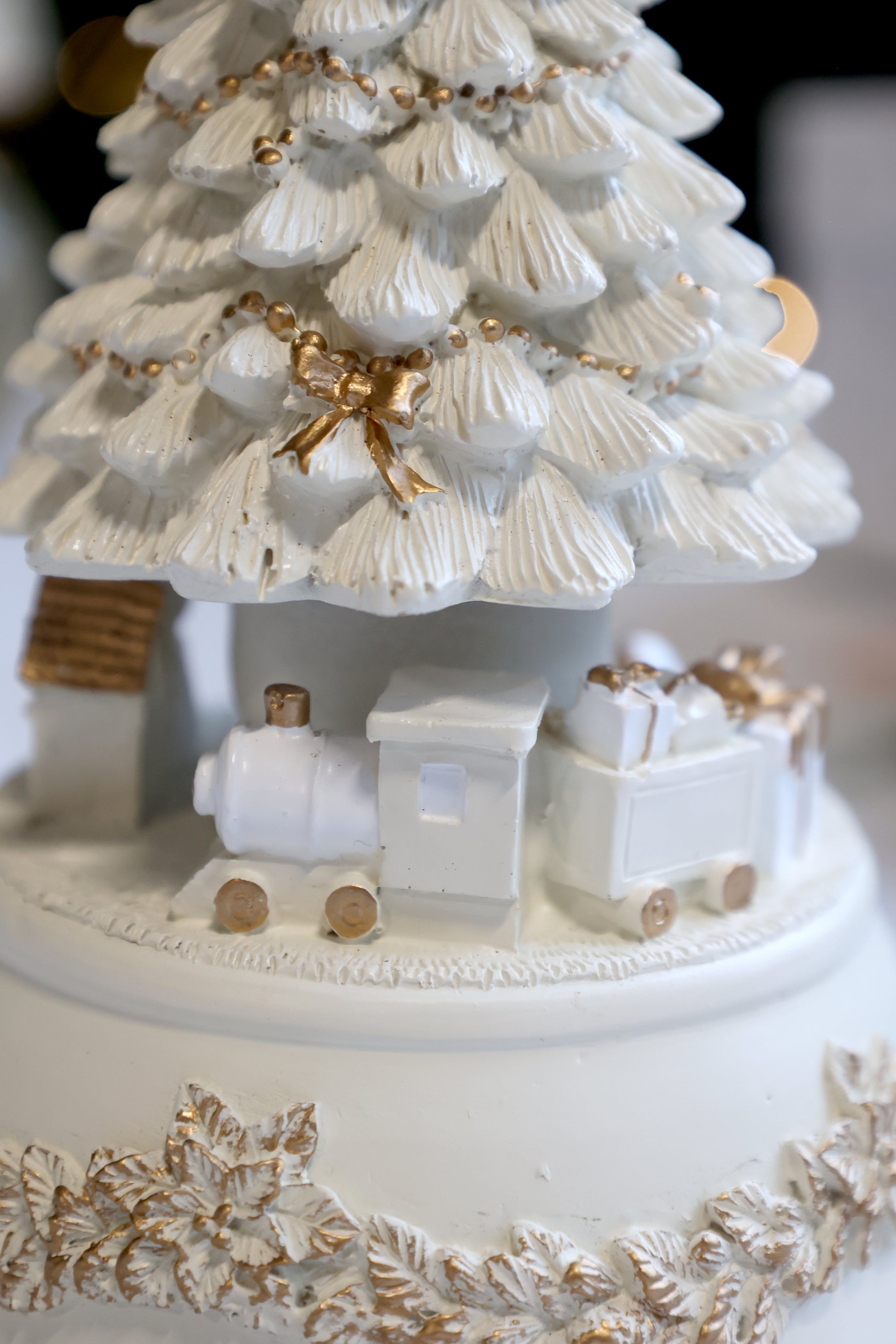 Decorative Christmas tree with a train and gold accents on a white background