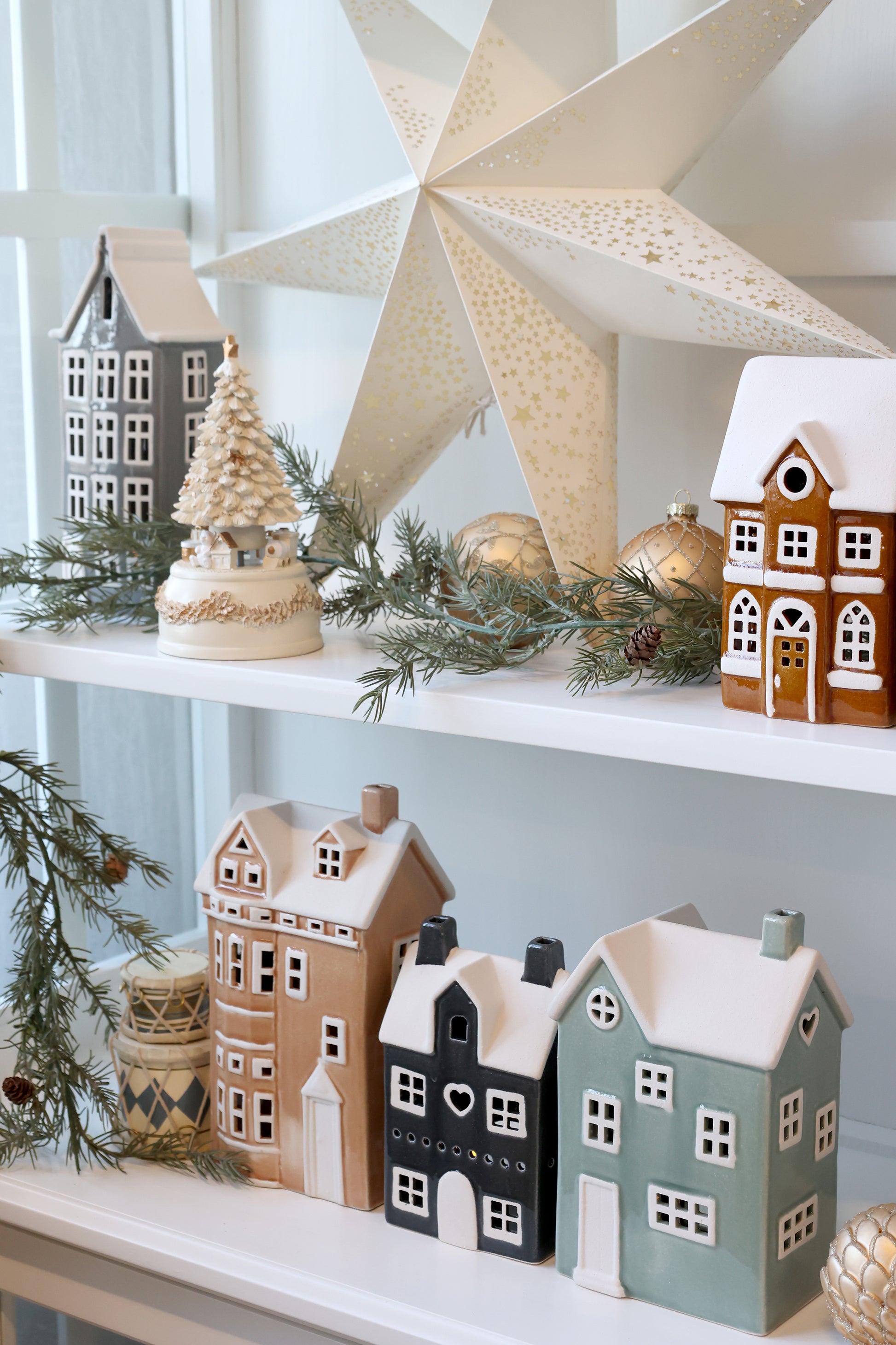 Decorative Christmas scene with miniature houses and a large star on a shelf.