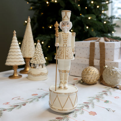 Decorative nutcracker figure on a table with Christmas decorations in the background