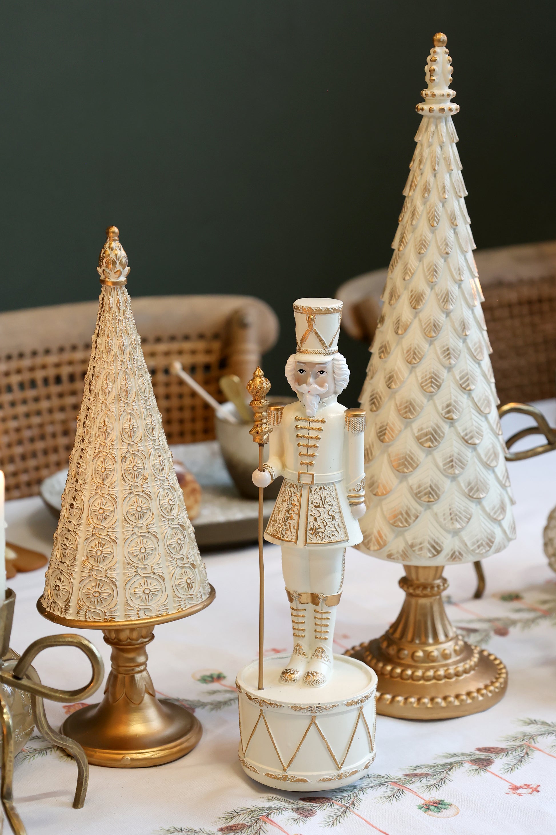 Decorative Christmas scene with a nutcracker and two gold and white trees on a table.