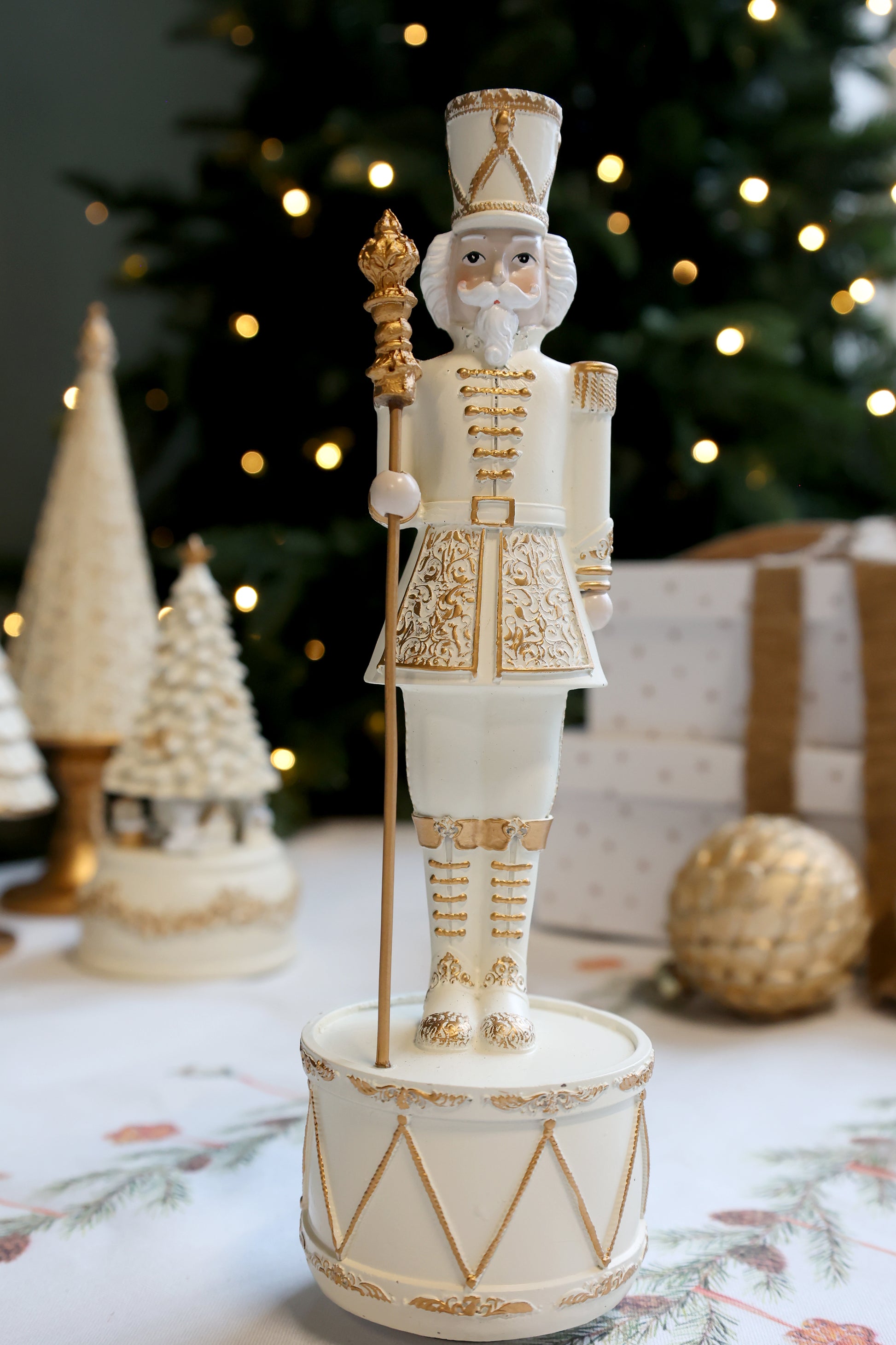 Decorative nutcracker figure with gold accents in front of a Christmas tree.