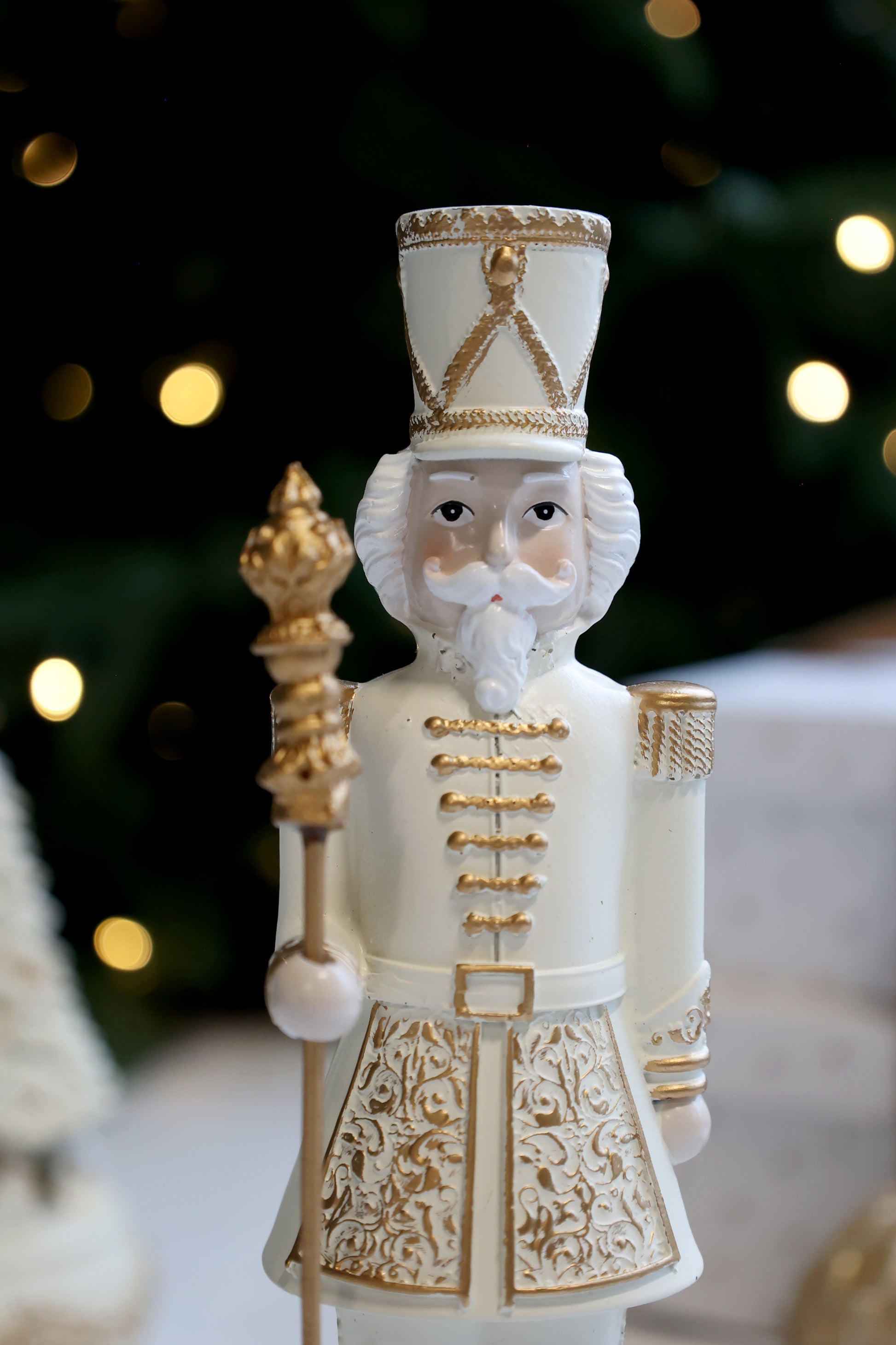Decorative nutcracker figure with gold accents against a blurred Christmas tree background
