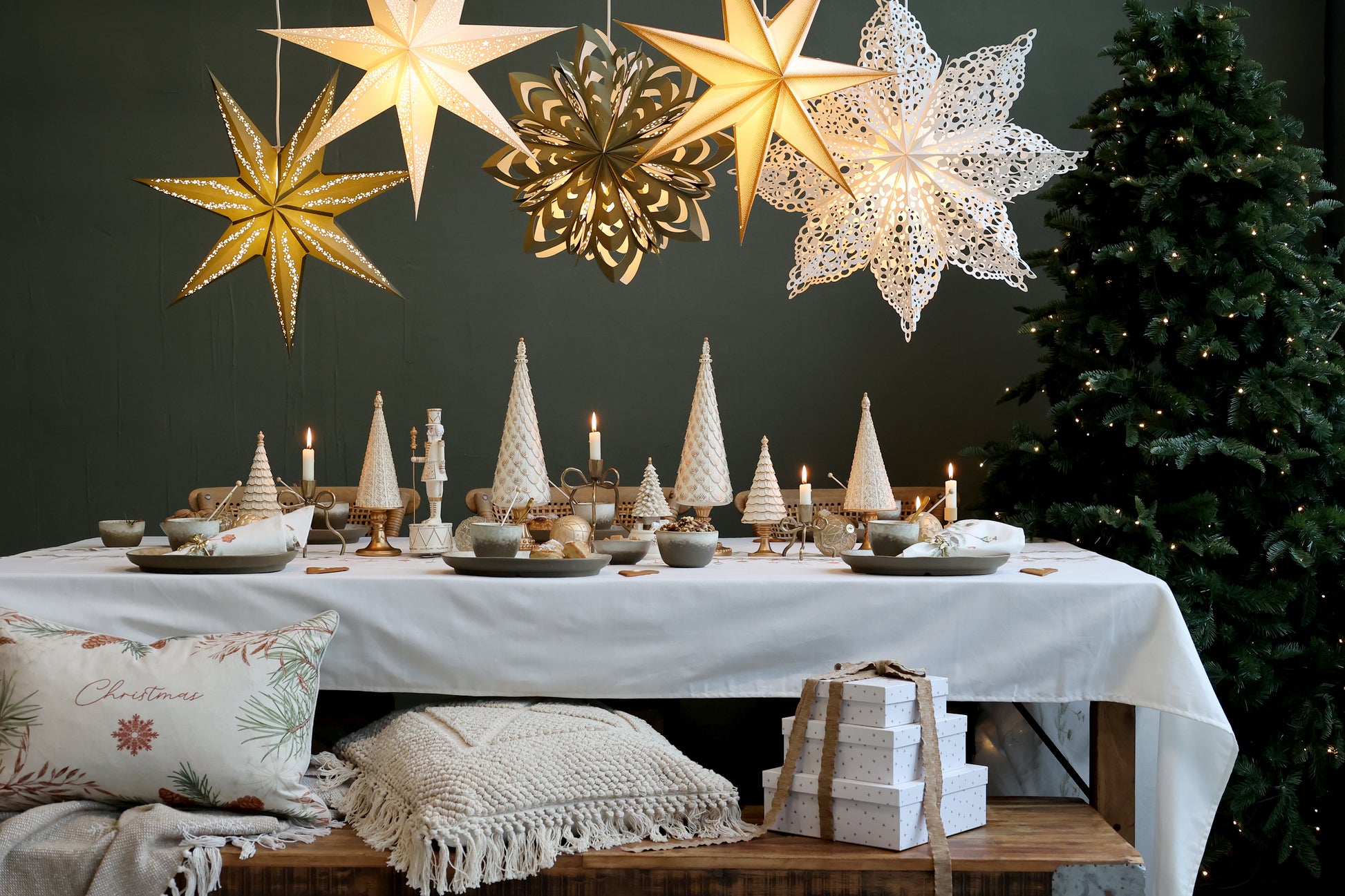 Decorated Christmas table with star-shaped lights and a tree in the background.