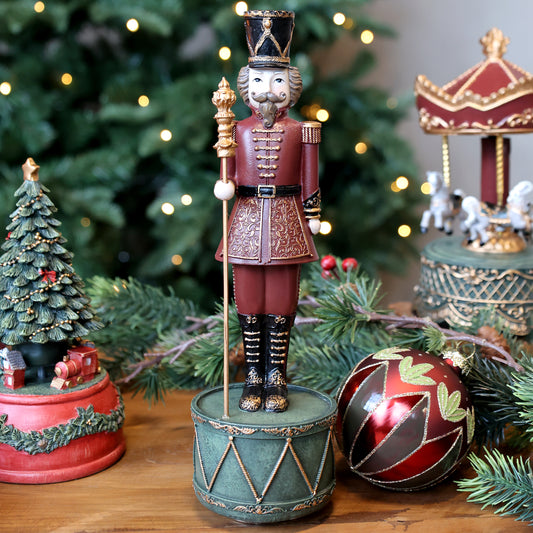 Decorative nutcracker figure with a Christmas tree and ornaments in the background