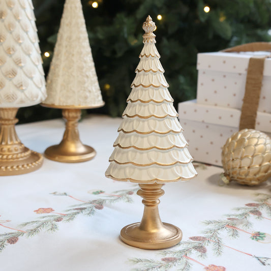 Decorative Christmas trees with gold bases on a festive tablecloth.