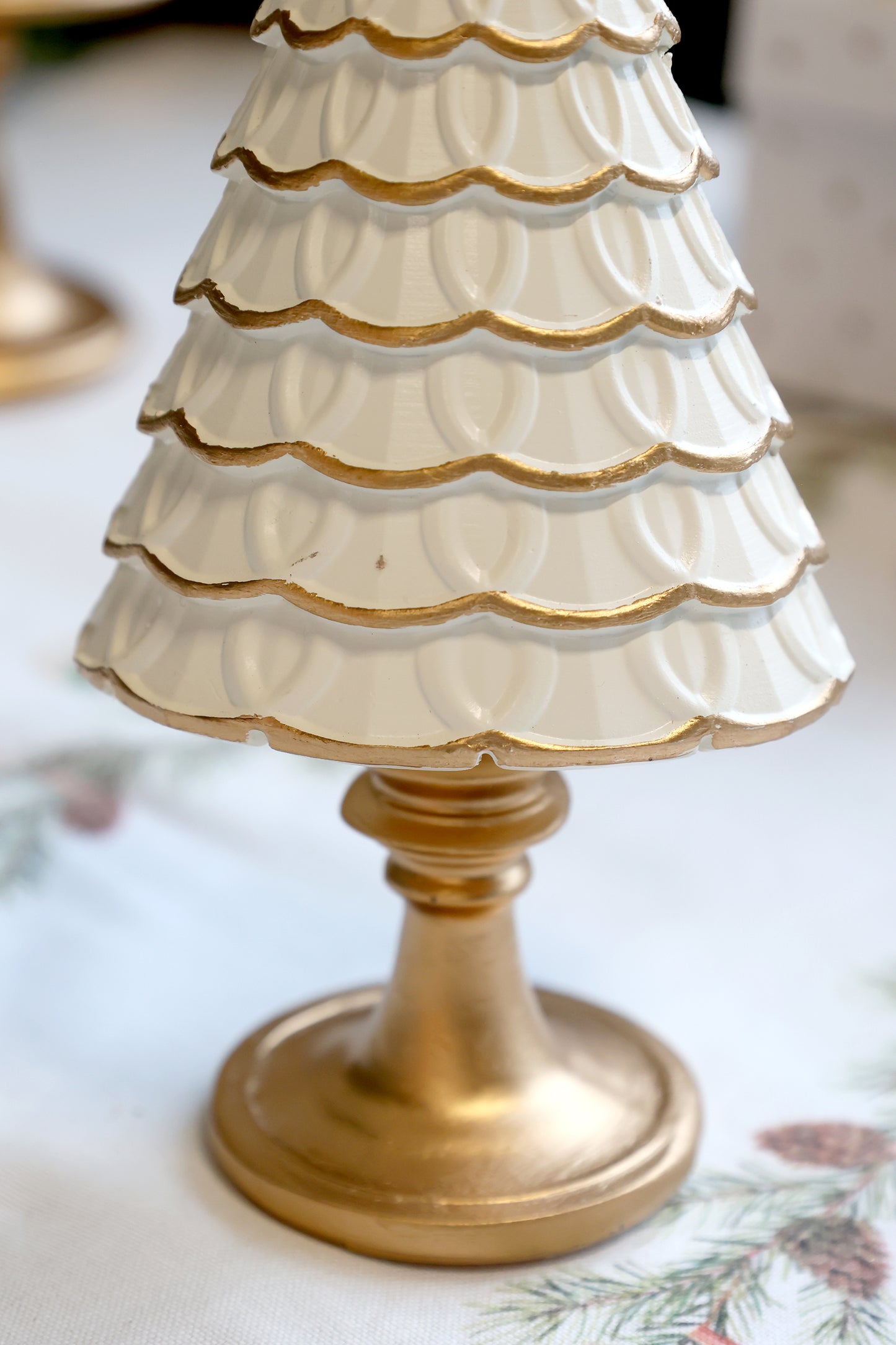 Decorative white and gold tree-shaped object on a floral tablecloth