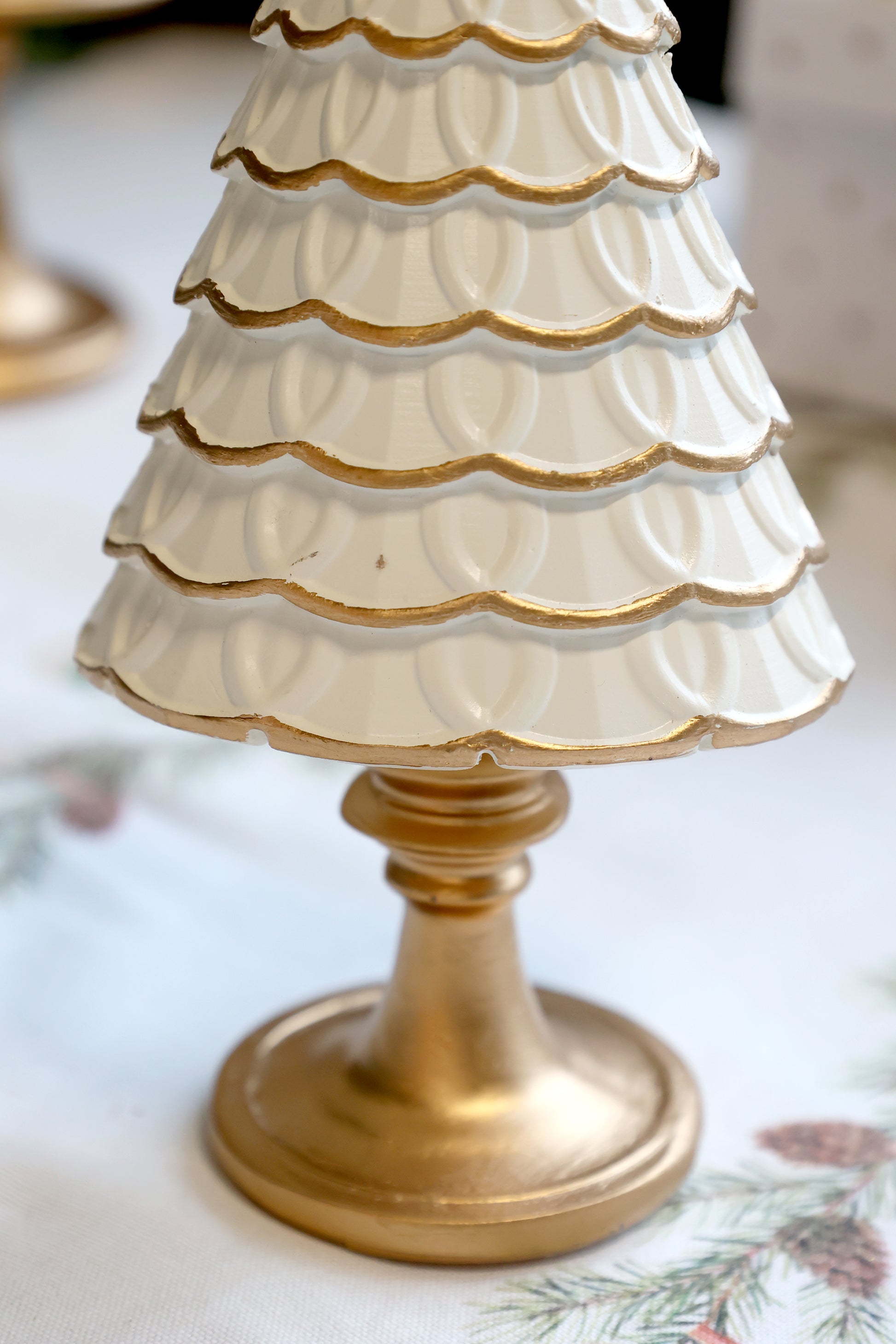 Decorative white and gold tree-shaped object on a floral tablecloth