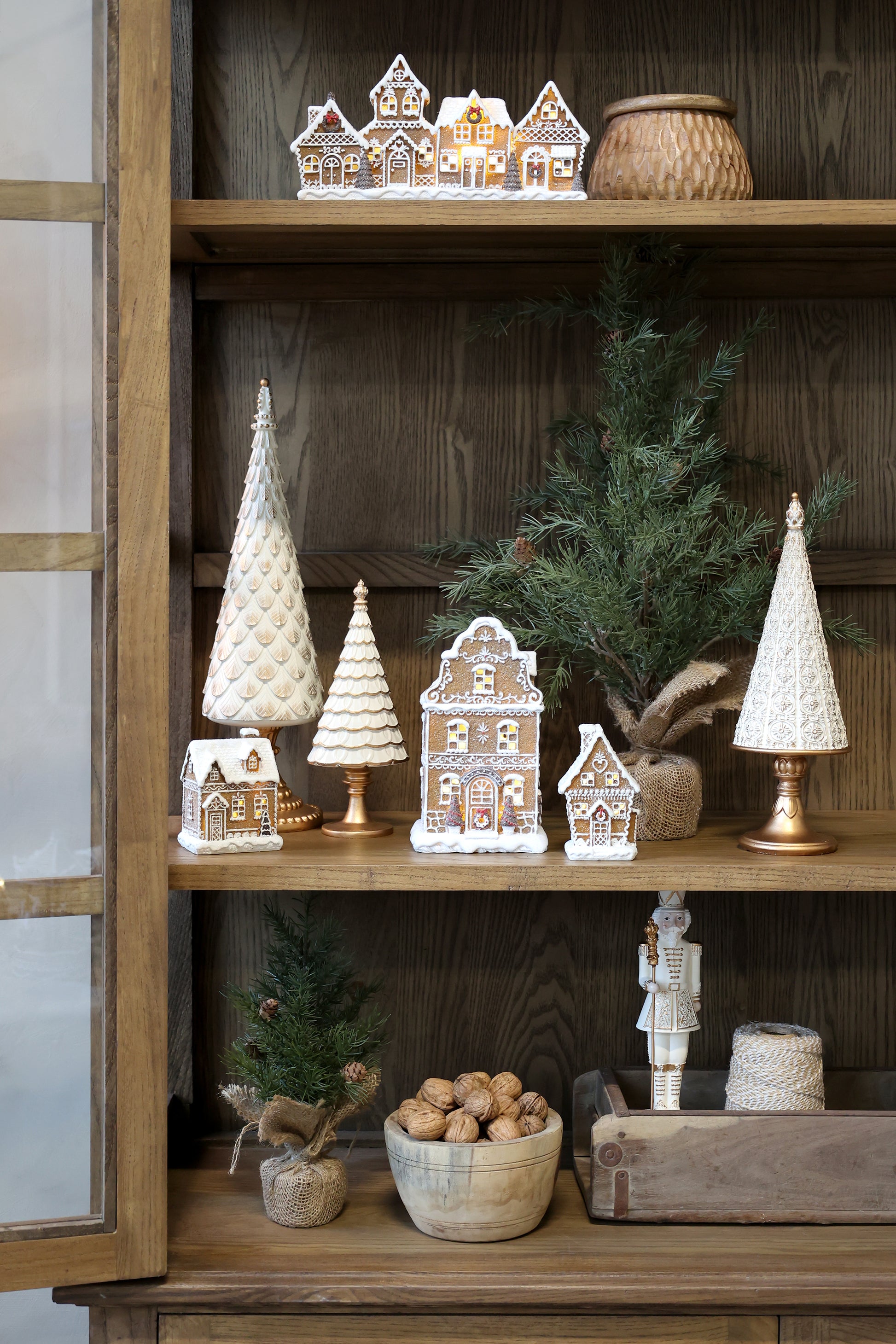 Decorative Christmas items on a wooden shelf including small houses, trees, and a nutcracker.