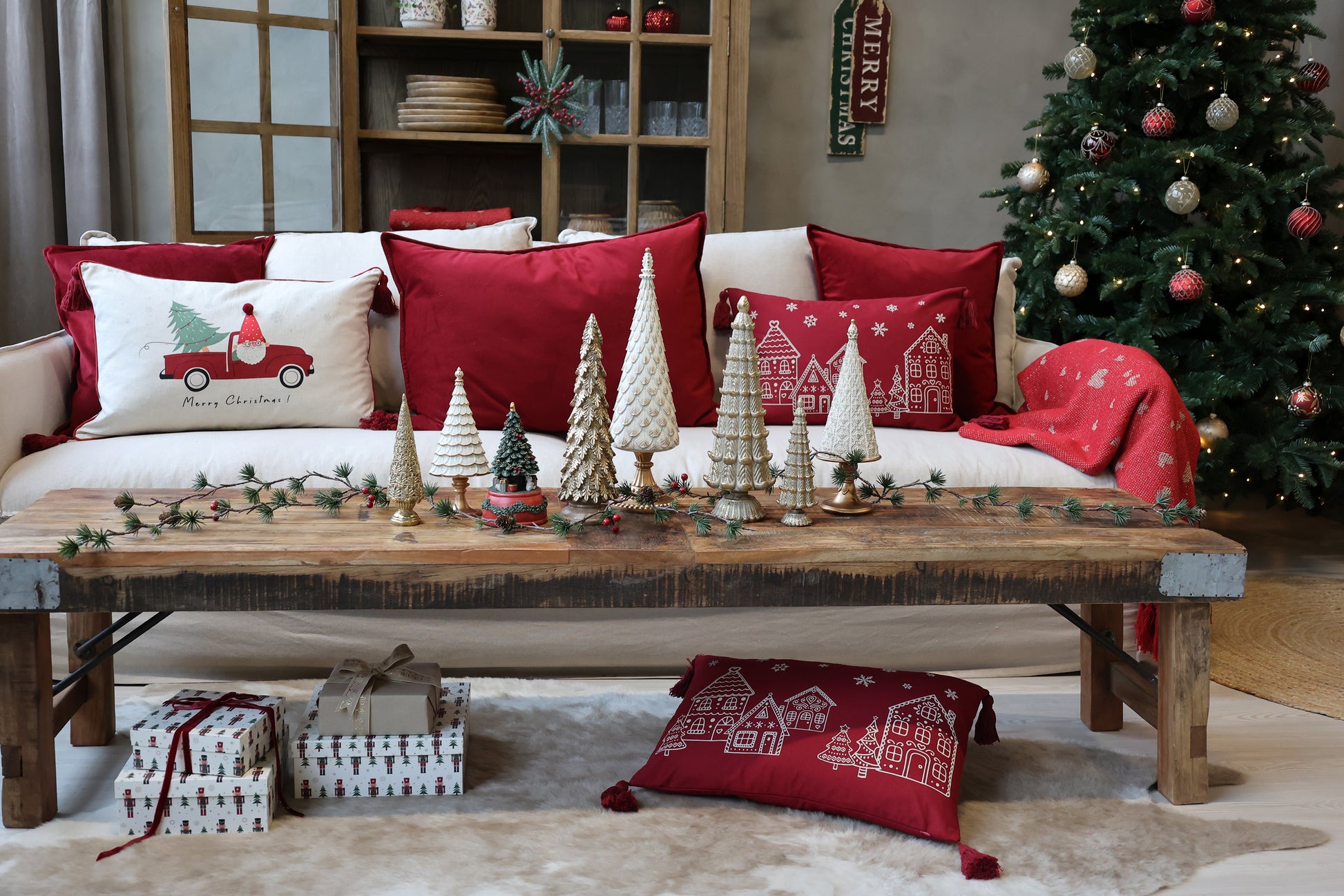 Living room with Christmas decor including a tree, pillows, and a coffee table with small trees.